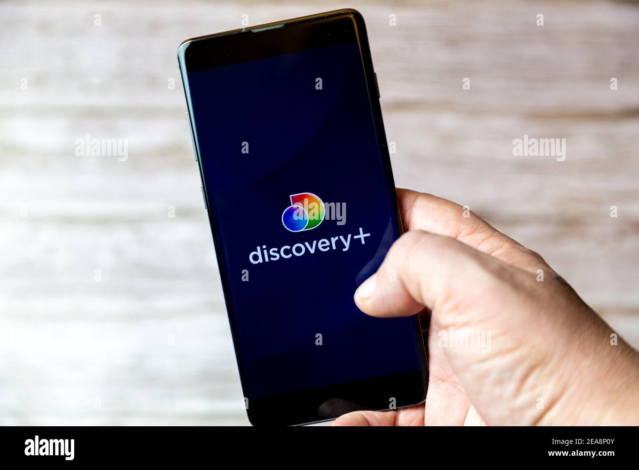 Un teléfono móvil o celular que se mantiene en un Mano con la aplicación Discovery Plus abierta en la pantalla Foto de stock