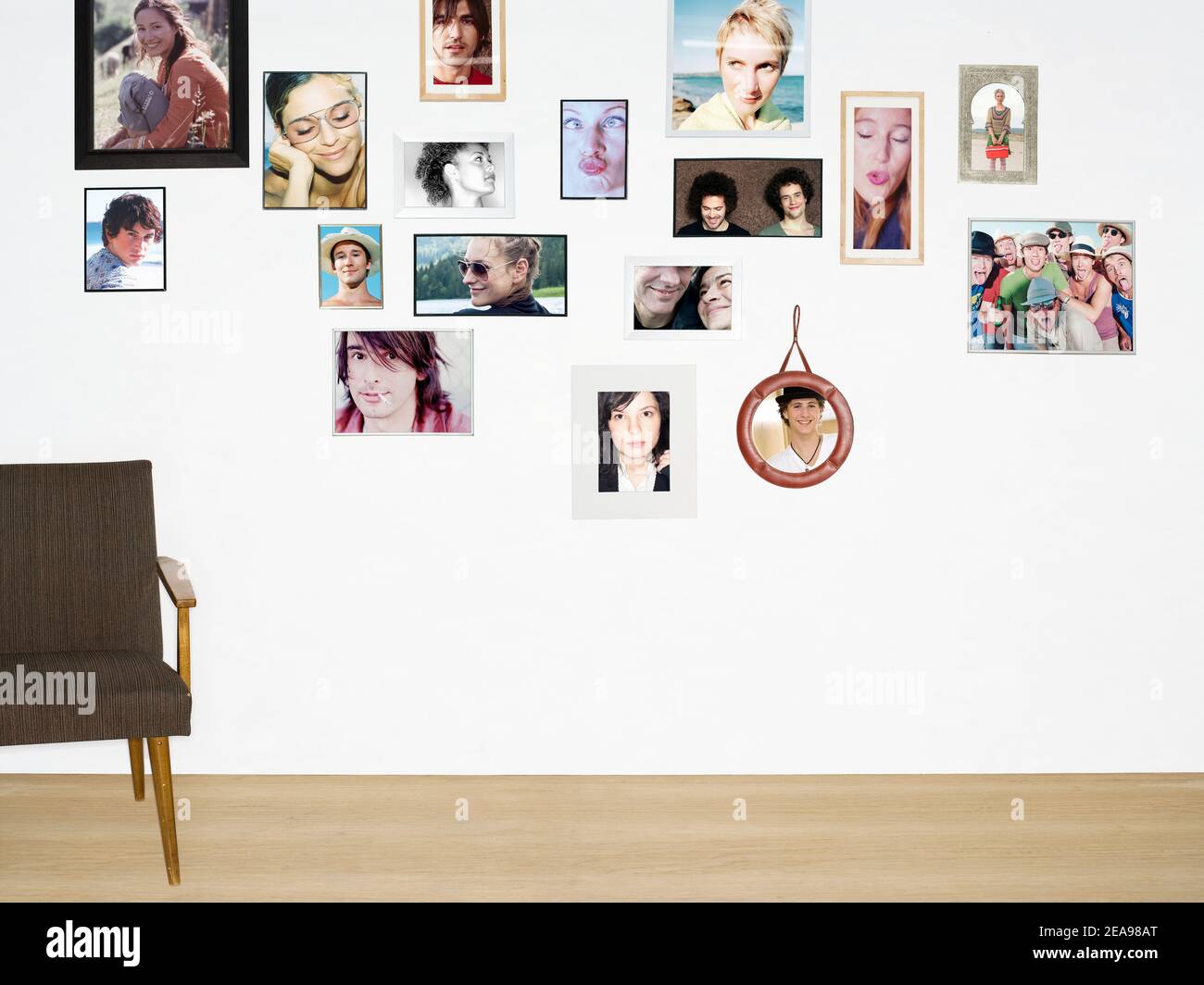 Pared con fotos de retratos de diferentes personas, en marcos de fotos, suelo de madera, silla vacía Foto de stock