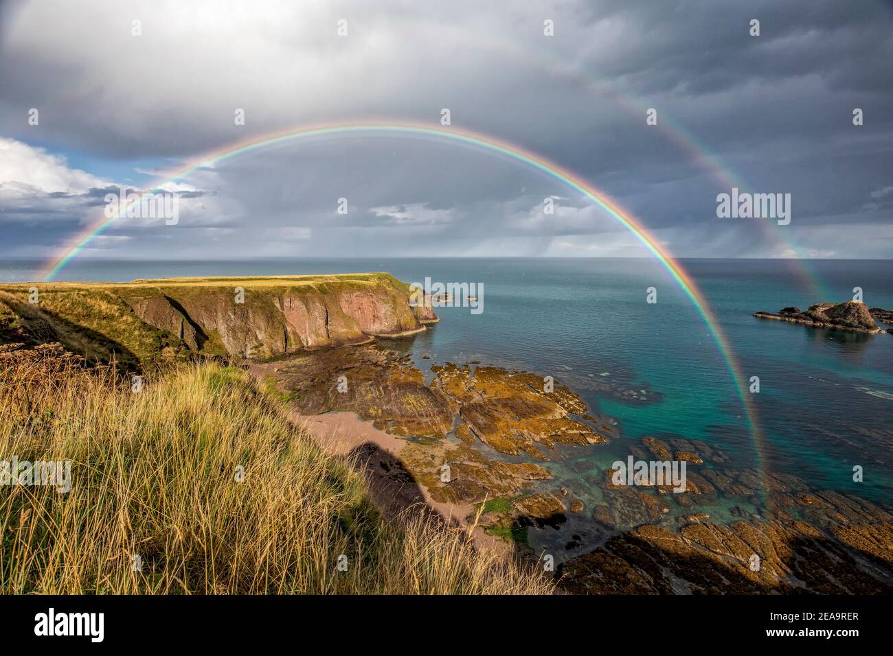 La costa escocesa en Stonehaven mirando hacia un cielo dramático y dos arco iris Foto de stock