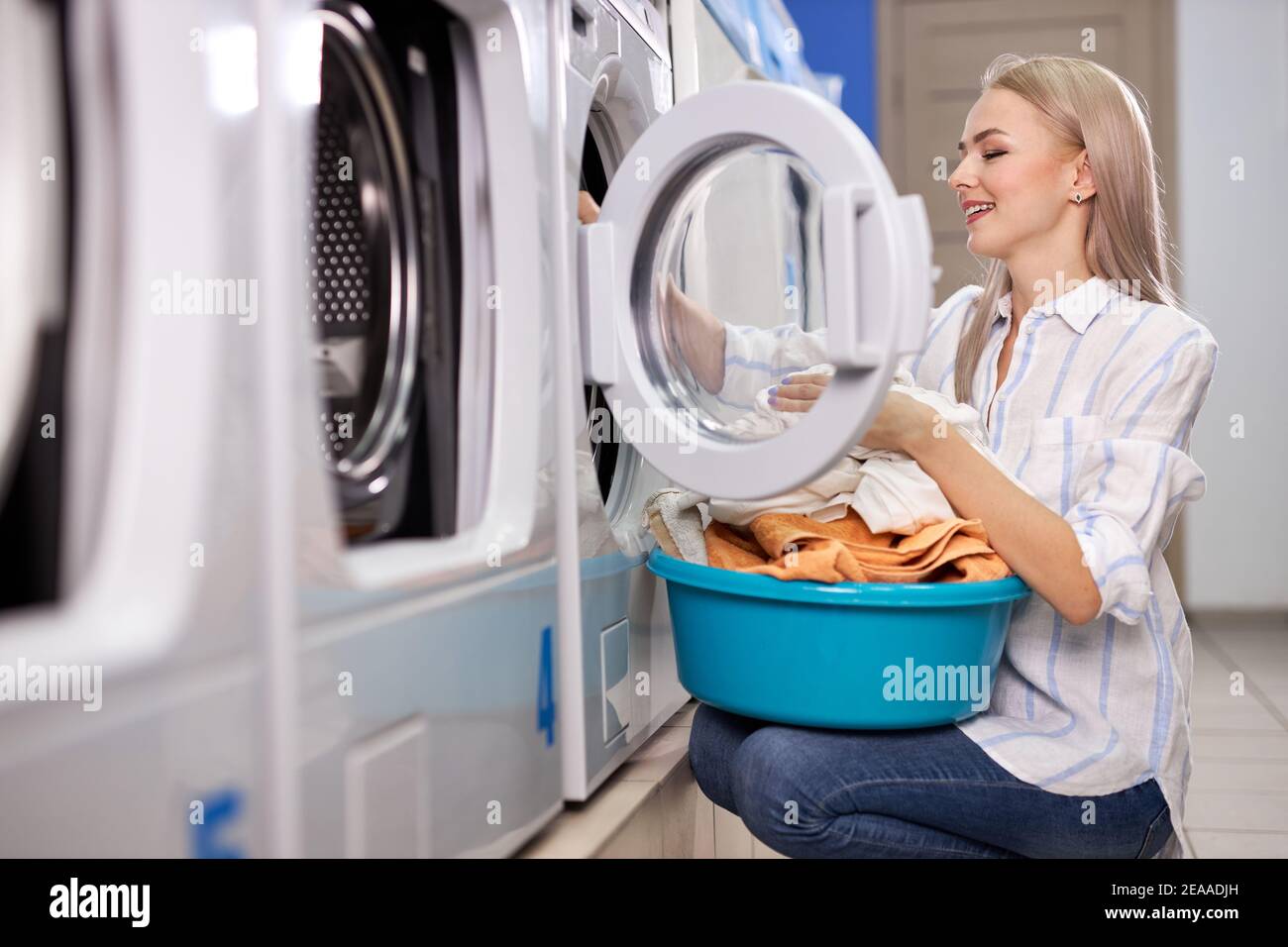 Mujer haciendo las tareas diarias - lavandería. Mujer ropa limpia doblada  en el lavamanos, vista lateral de la mujer disfrutando del proceso de  limpieza en el lavado Fotografía de stock - Alamy