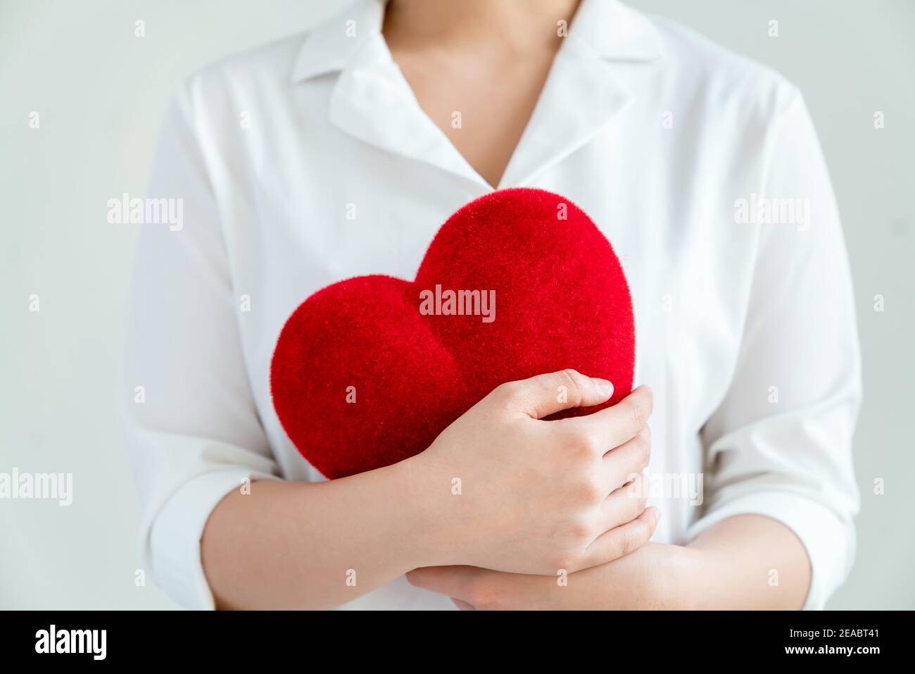 Mujer en una camisa blanca con corazones rojos sobre fondo gris