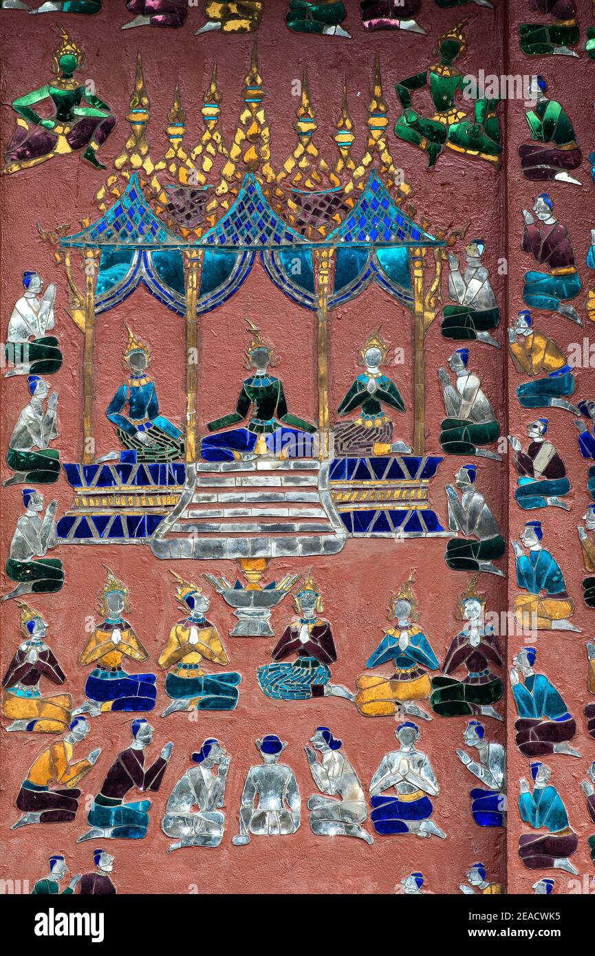 Escenas de la vida rural como decoraciones de mosaico en una pared exterior de la biblioteca Tripitaka, templo Wat Xieng Thong, Luang Prabang, Laos Foto de stock