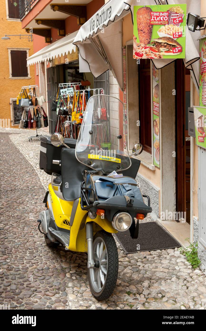 Piaggio Liberty scooter en el Poste Italiane S.p.A. Livery estacionado fuera de una tienda en Malcesine, Lago de Garda, Italia. Foto de stock