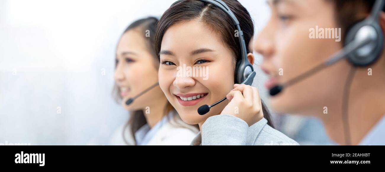 Sonriente hermosa mujer asiática agente de telemarketing trabajando con el equipo en fondo de banner de oficina del centro de llamadas con espacio para copias Foto de stock