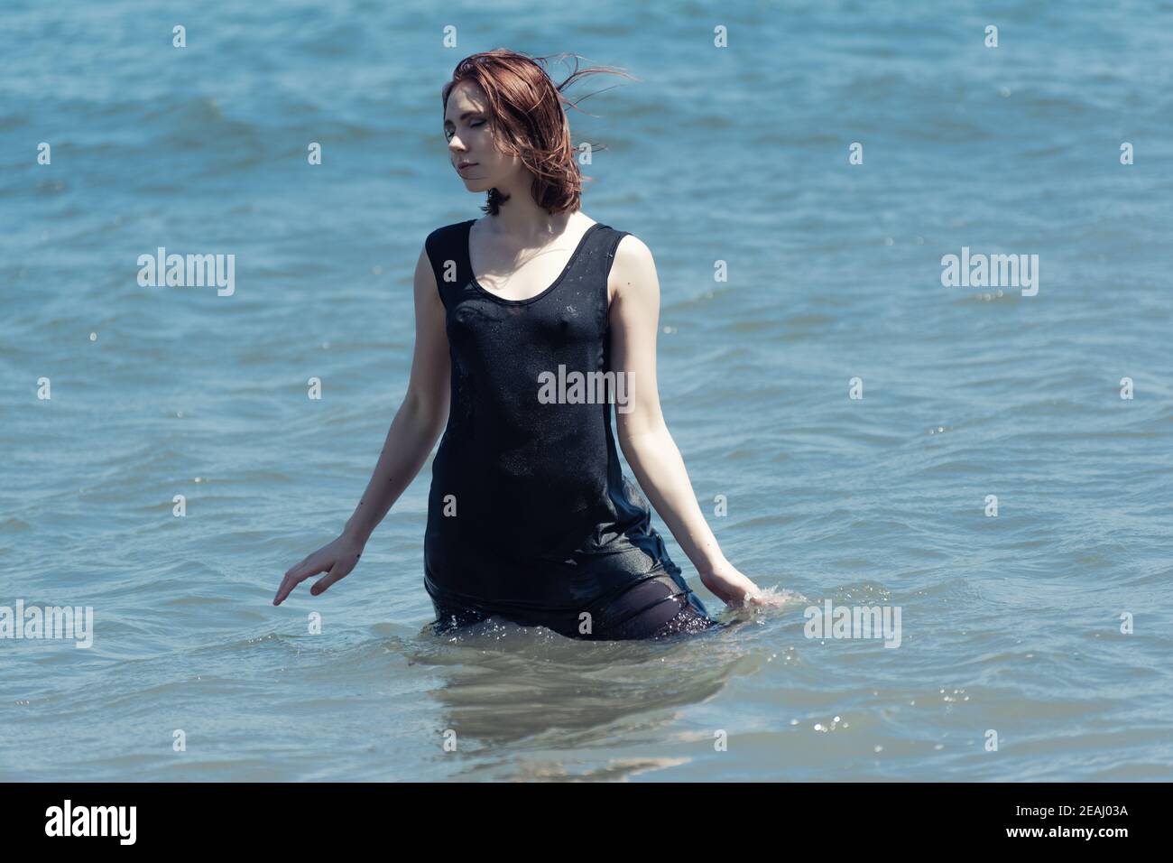 La joven con vestido negro disfruta del mar. Foto de stock