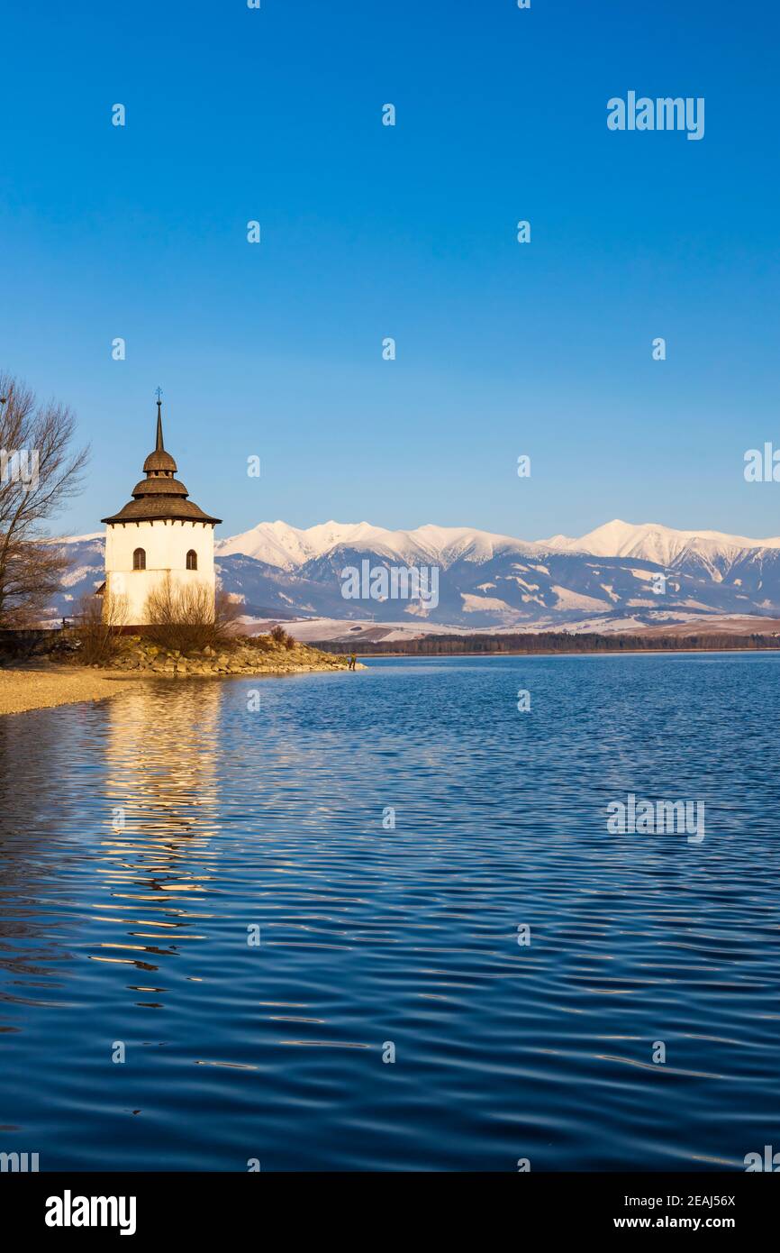 Iglesia de la Virgen María en Havanok y el lago Liptovska Mara, distrito Liptovsky Mikulas, Eslovaquia Foto de stock