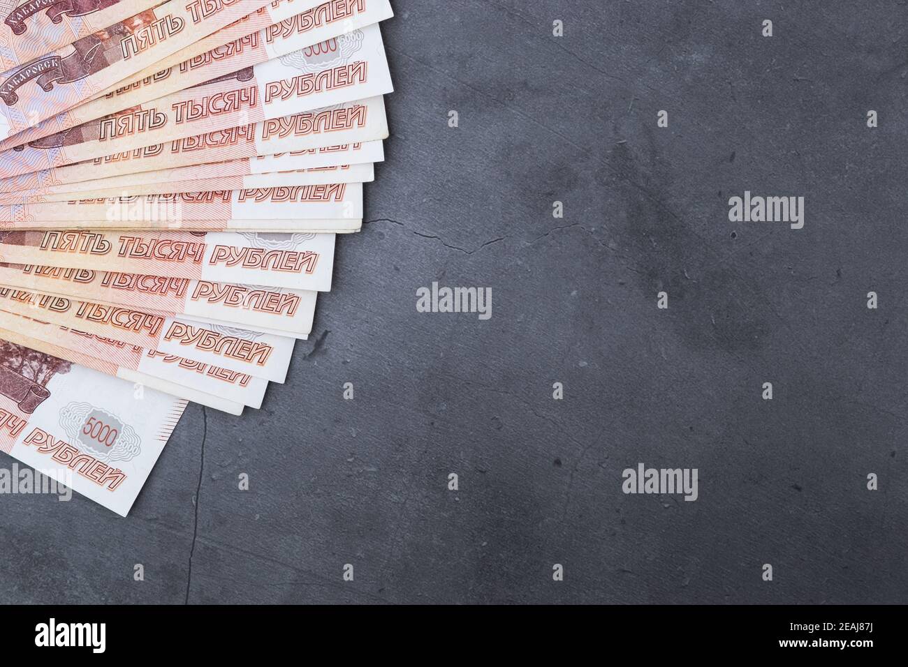 Gran pila de billetes de dinero ruso de cinco mil rublos ventilador tumbado sobre un fondo de cemento gris. Foto de stock