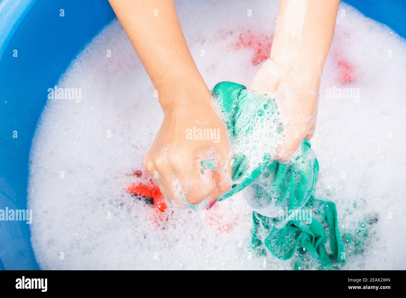 El bebé se baña o se lava en una palangana con espuma y pompas de jabón.