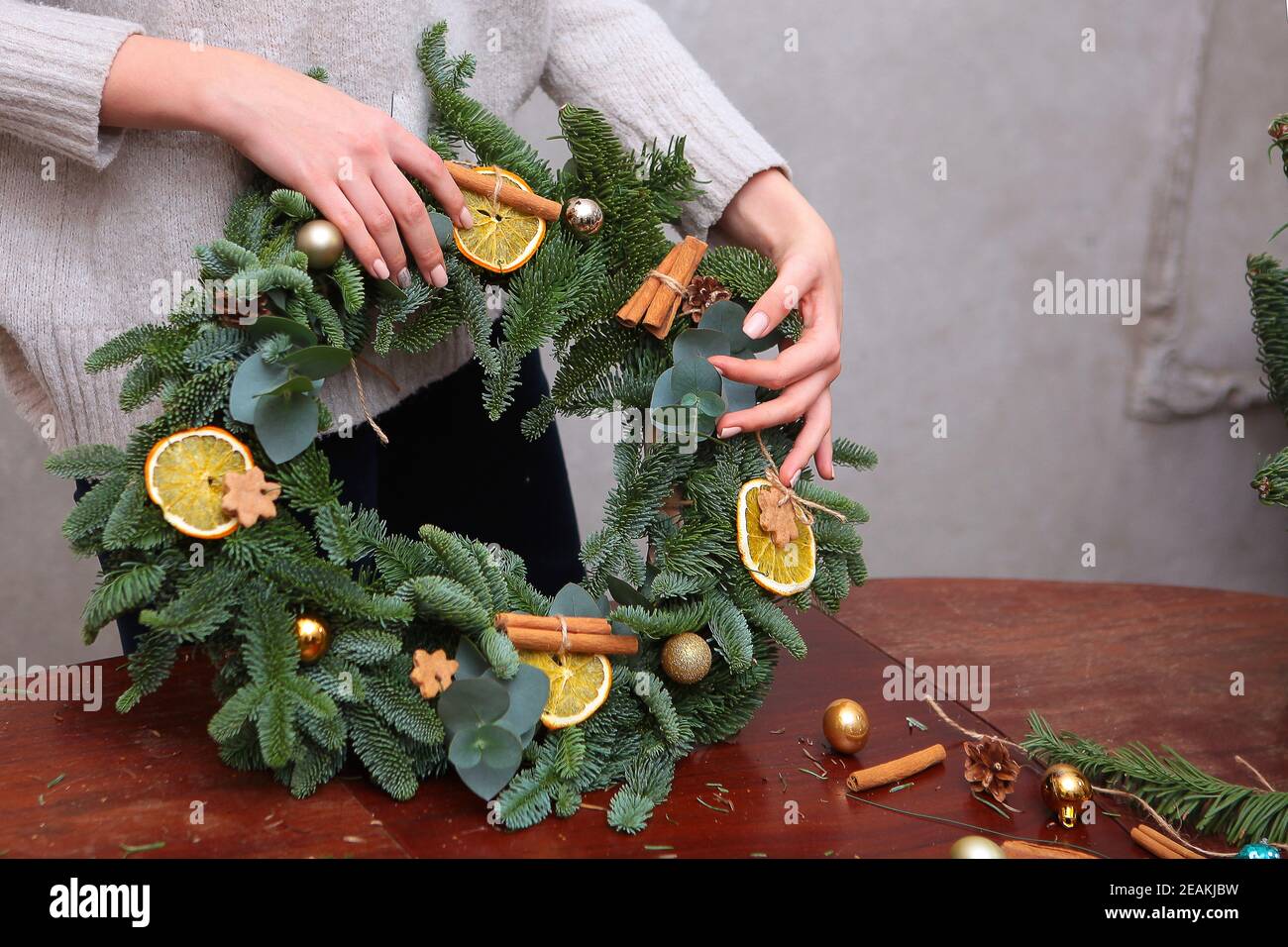 La decoración navideña está hecha a mano. La tradicional corona navideña está decorada con naranjas y canela. Fotos sin cara. Foto de stock