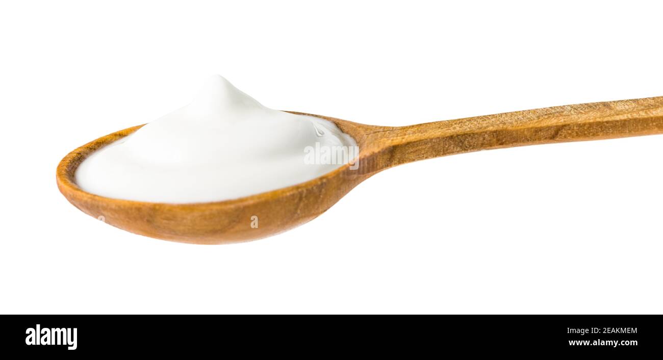 Yogur en cuchara de madera Foto de stock