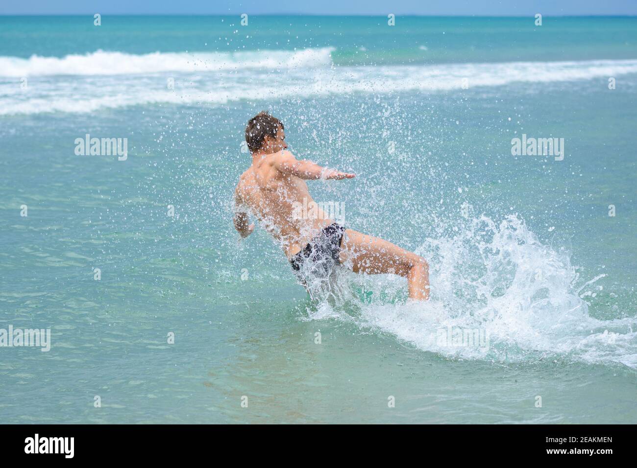 Un hombre que acelera desde la orilla salta de lado en el agua de mar en el complejo Foto de stock