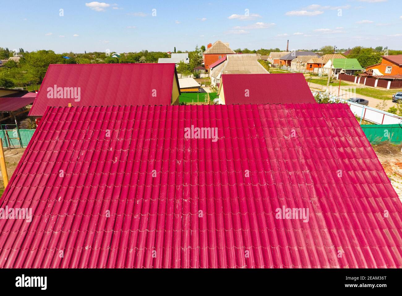 Una casa con tejado rojo hechas de planchas de metal corrugado. El techo de metal corrugado de perfil. Azulejos de metal. Foto de stock