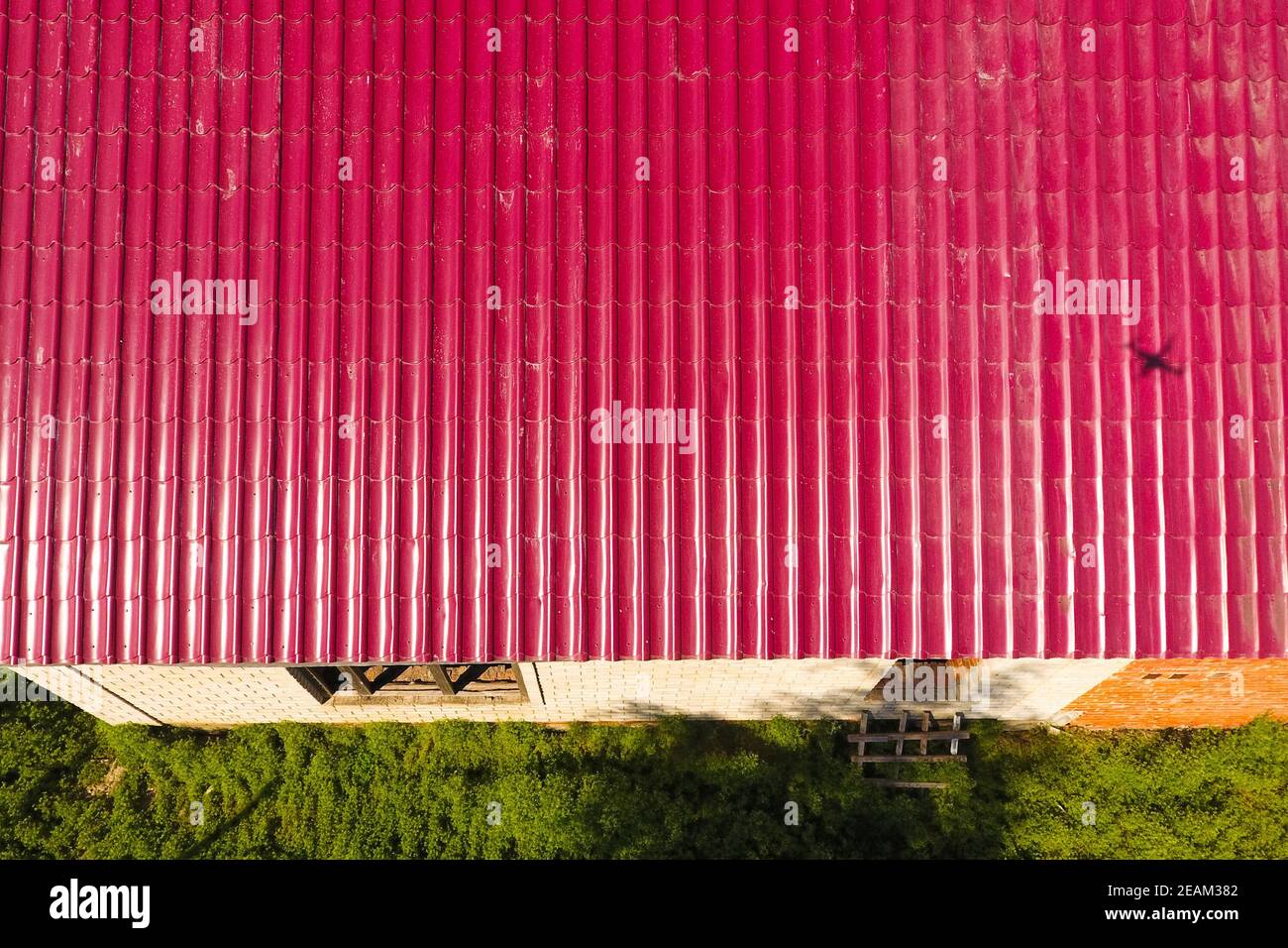 Una casa con tejado rojo hechas de planchas de metal corrugado. El techo de metal corrugado de perfil. Azulejos de metal. Foto de stock