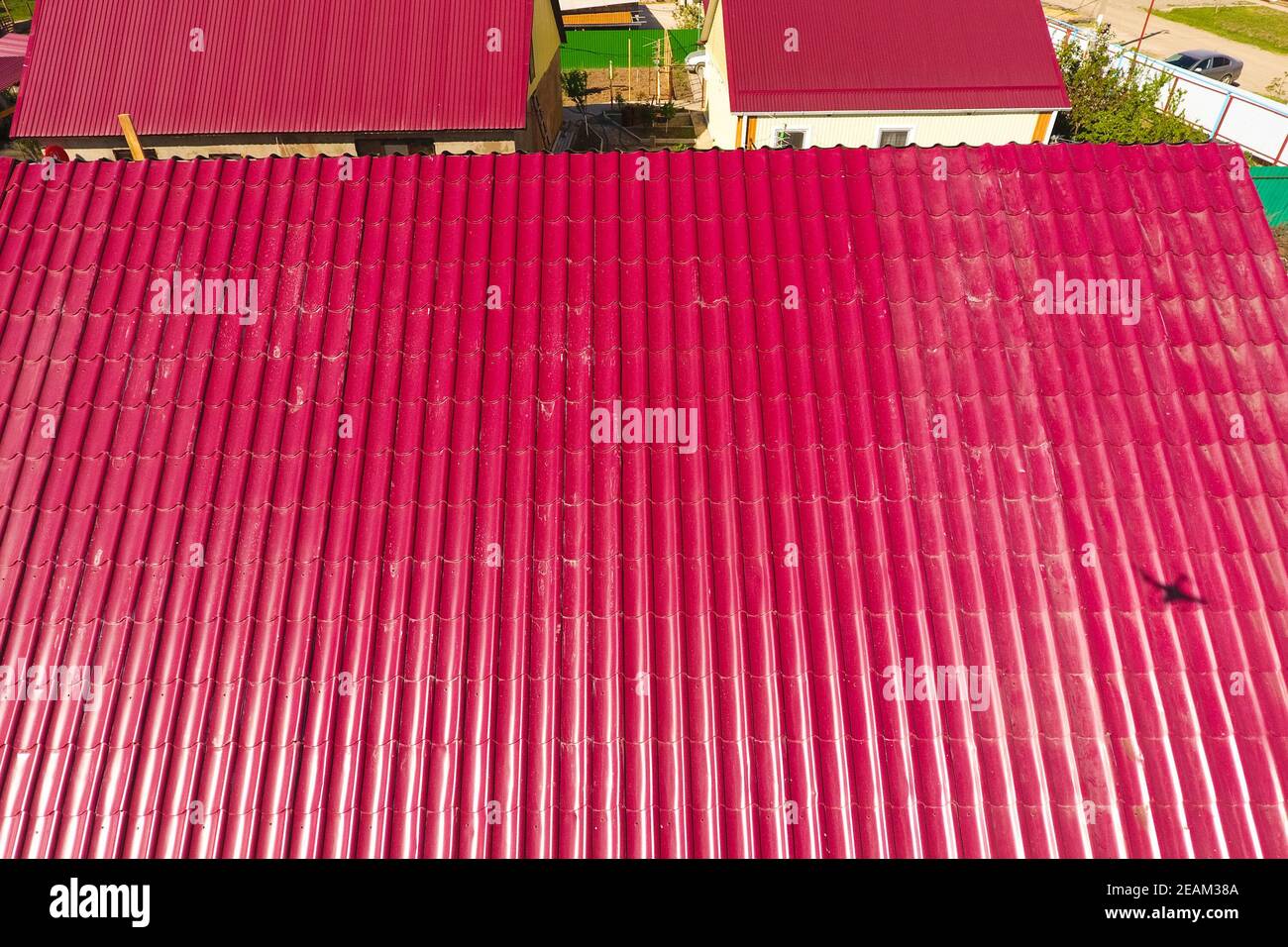 Una casa con tejado rojo hechas de planchas de metal corrugado. El techo de metal corrugado de perfil. Azulejos de metal. Foto de stock