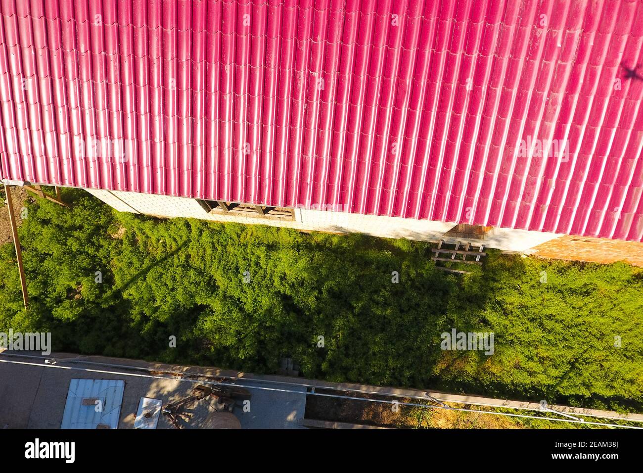 Una casa con tejado rojo hechas de planchas de metal corrugado. El techo de metal corrugado de perfil. Azulejos de metal. Foto de stock