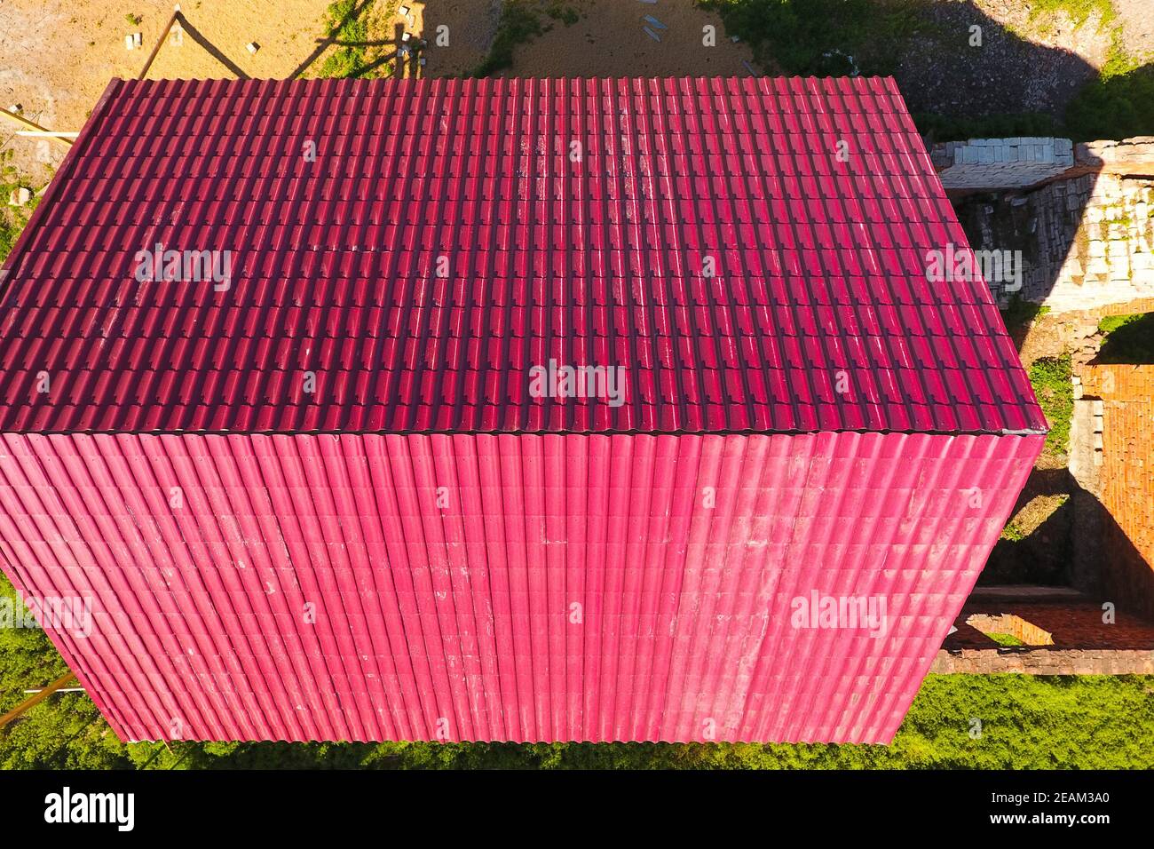 Una casa con tejado rojo hechas de planchas de metal corrugado. El techo de metal corrugado de perfil. Azulejos de metal. Foto de stock