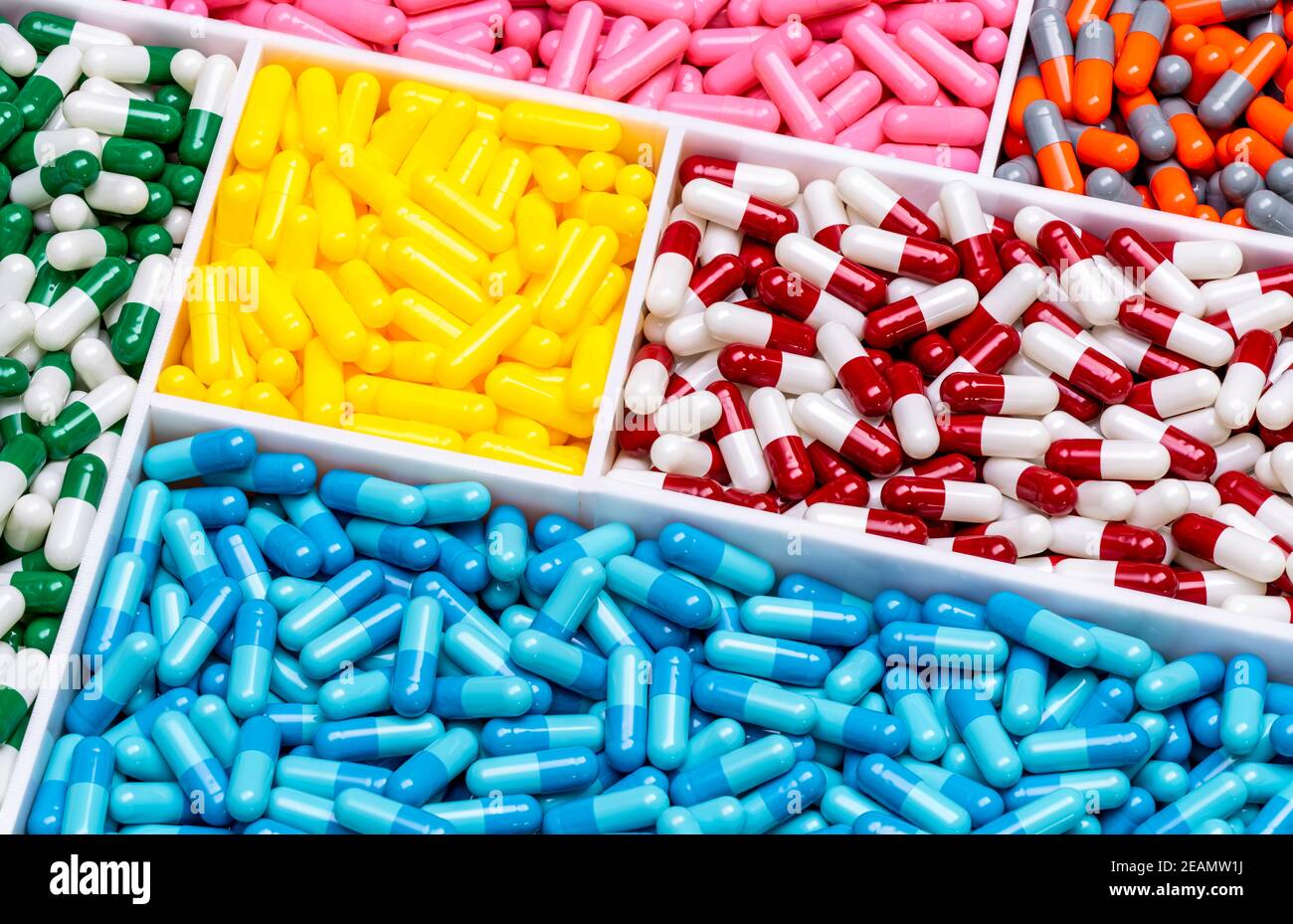 Vista superior de las pastillas de cápsulas de colores en la bandeja de plástico Industria farmacéutica. Salud y medicina. Producción de drogas. Concepto farmacéutico. Vitaminas y suplementos cápsulas. Cápsula de color brillante. Foto de stock