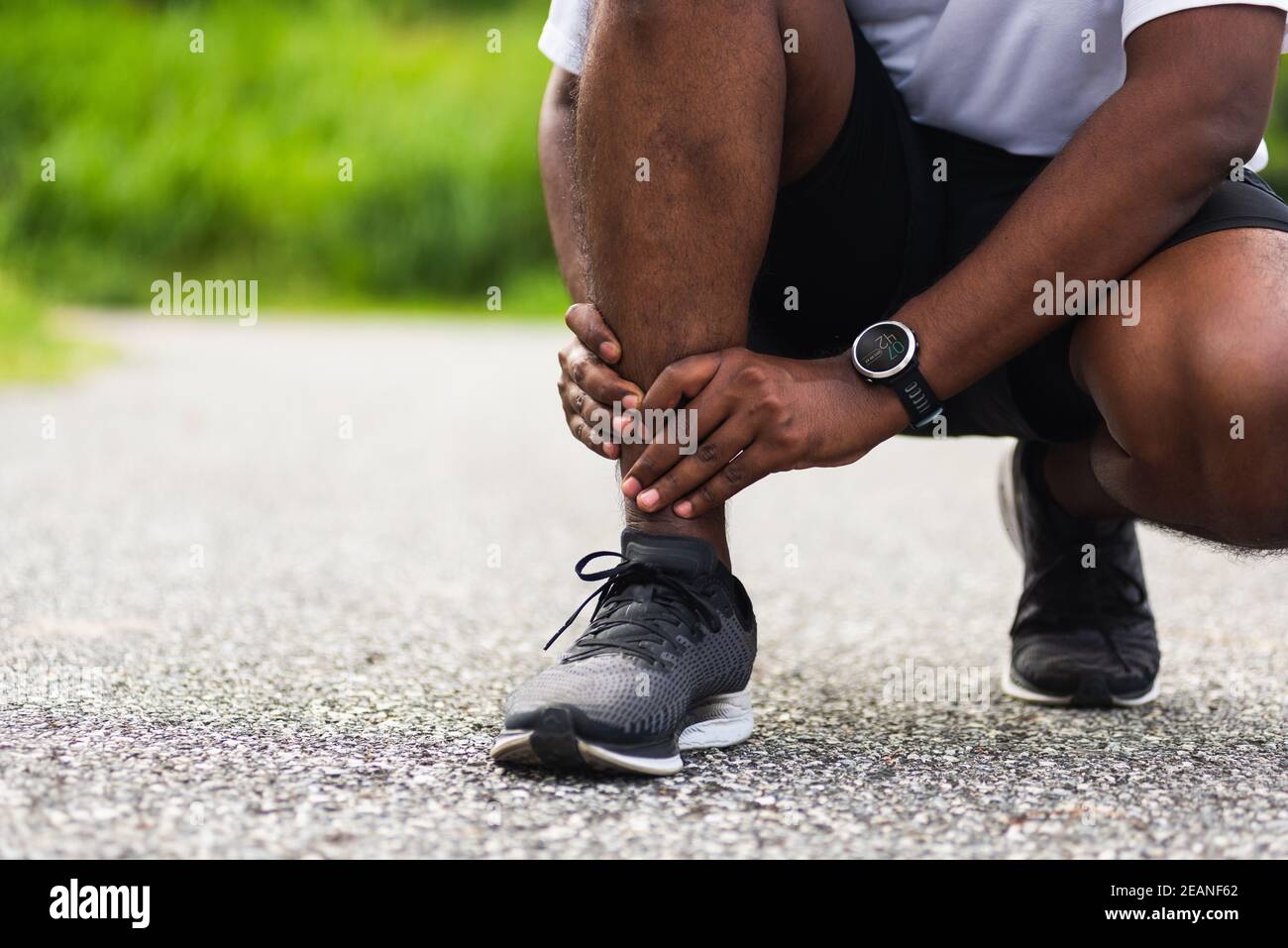 el hombre corredor de deporte usa las manos articulación sostener el dolor de la pierna porque de tobillo torcido roto mientras corres Foto de stock