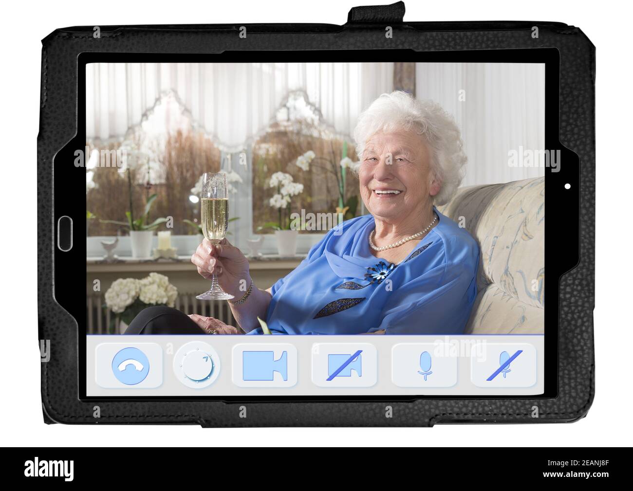 PC Tablet aislado muestra una aplicación diseñada imaginaria para videollamadas de personas mayores. Los botones son grandes y claros. En la pantalla hay una alegre mujer mayor en casa con una copa de champán. Ella Salud. Foto de stock