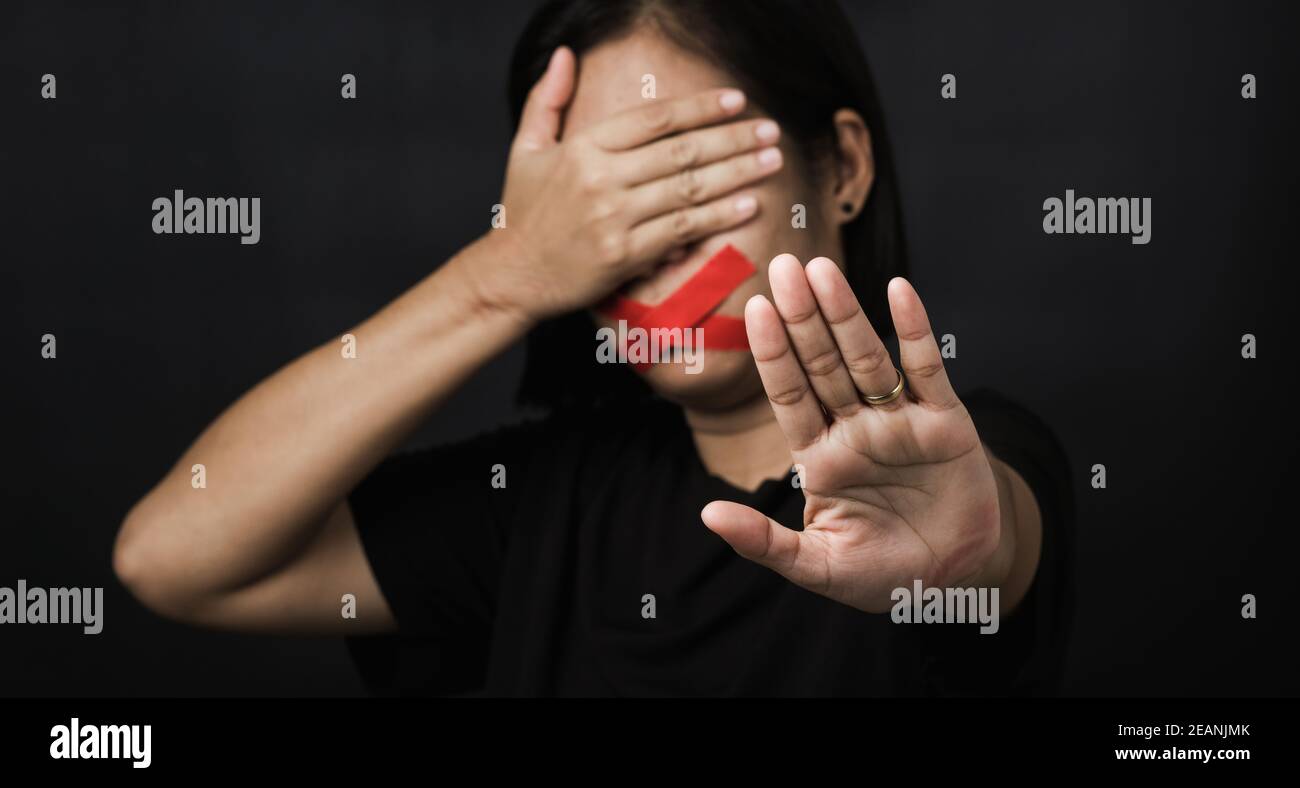 Mujer envolviendo la boca con cinta adhesiva y mostrar la señal de la mano detener abusar de la violencia Foto de stock