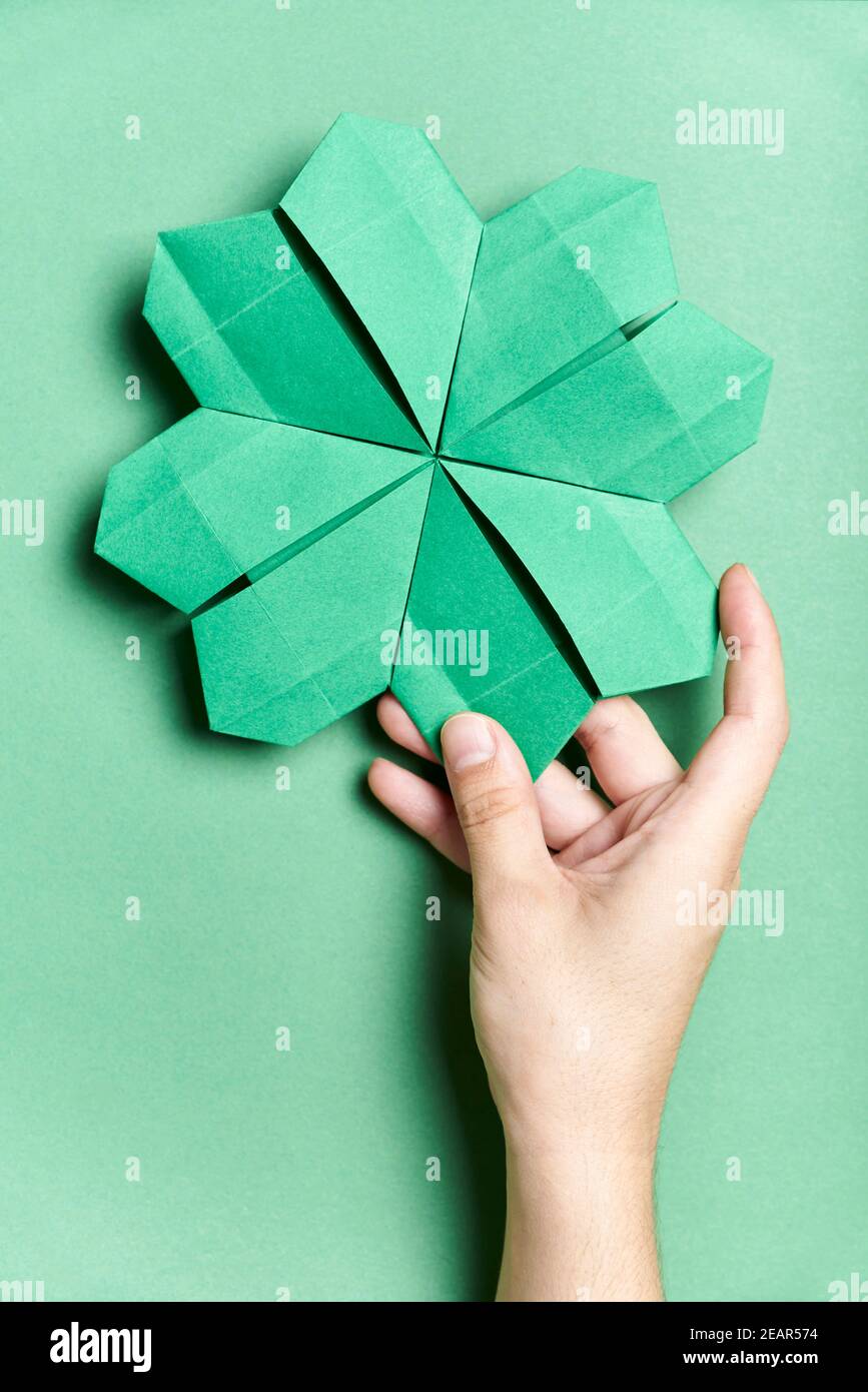 Trébol de cuatro hojas hecho de papel, origami, sostenido por una mano de  una joven sobre fondo verde. Conceptos de suerte y día de San Patricio  Fotografía de stock - Alamy