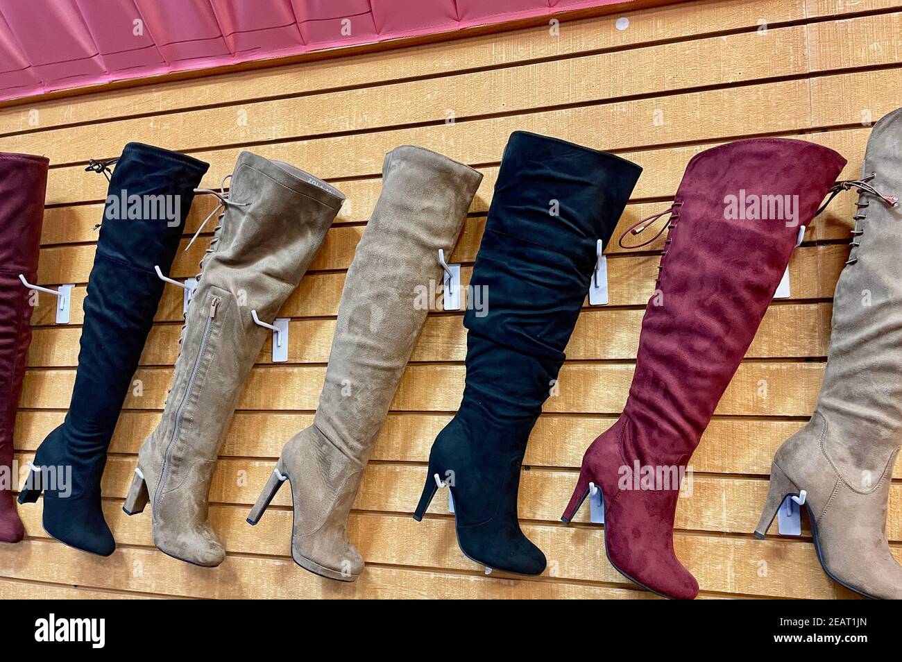 Fila de botas altas con tacones altos en diferente colores que muestran en la pared de la tienda Fotografía de stock - Alamy