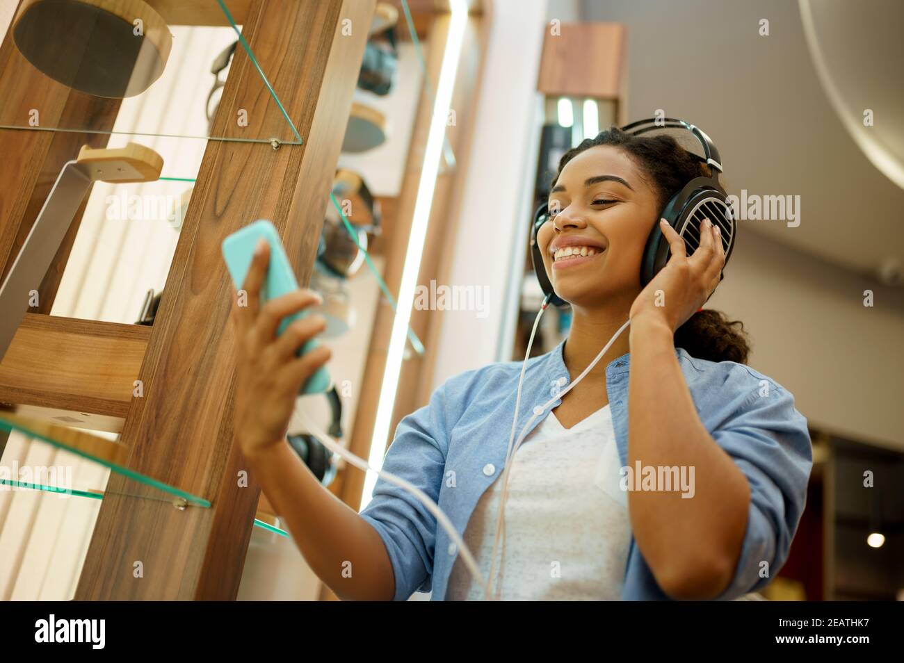 Mujer escuchando música en la tienda de auriculares Foto de stock