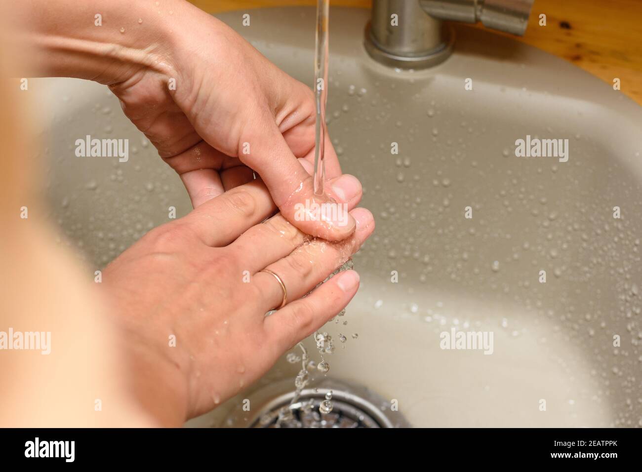Las manos de la chica bajo el agua corriente del grifo en el lavabo Foto de stock