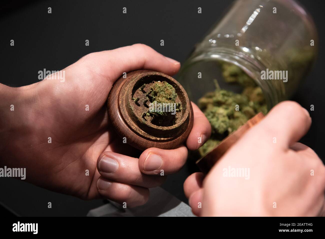 Cannabis en un molinillo y otros utensilios para fumar en un tabla Foto de stock
