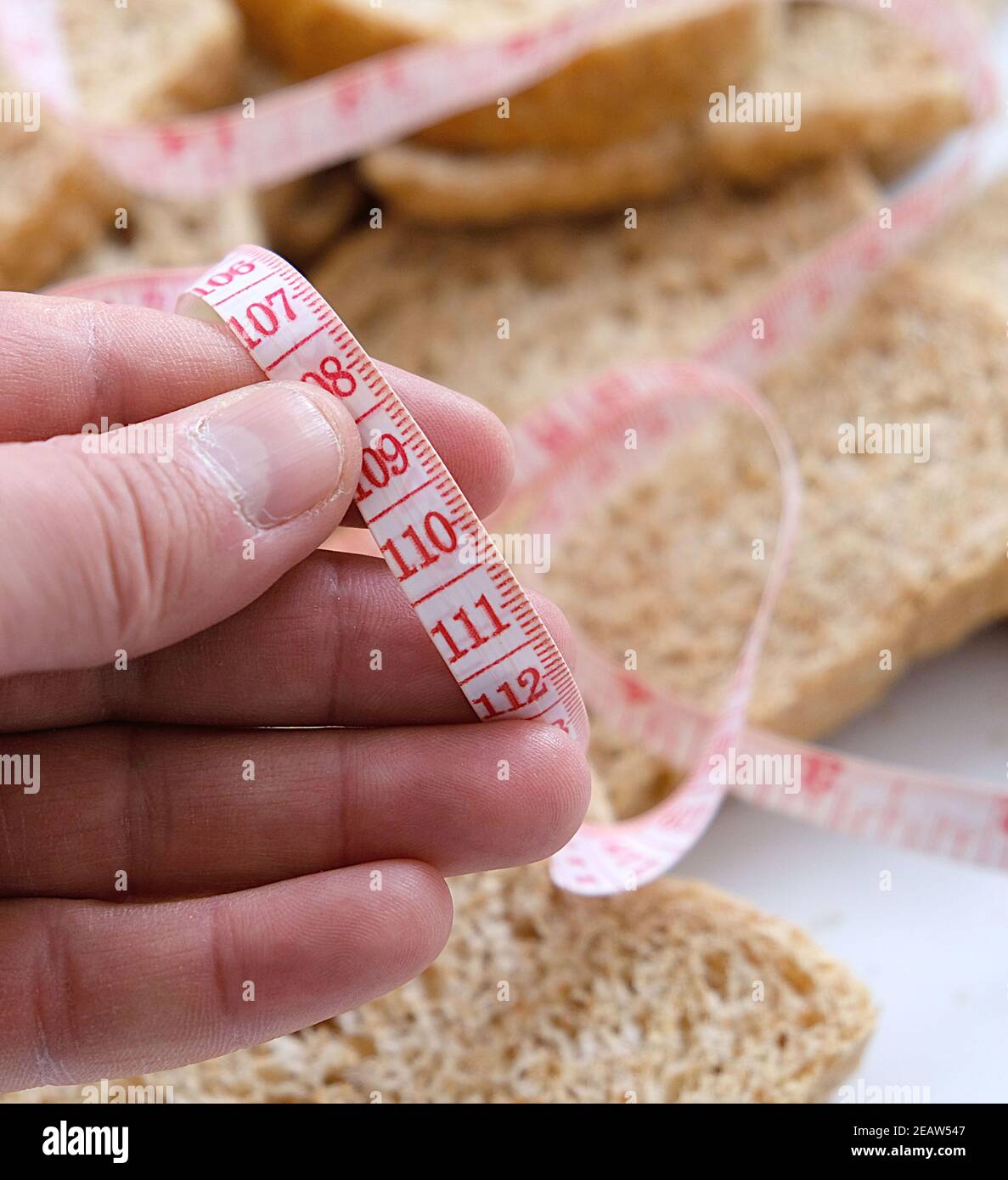 Contra el aumento excesivo de peso en casa, pan de salvado, rebanadas de pan de salvado y una cinta métrica Foto de stock