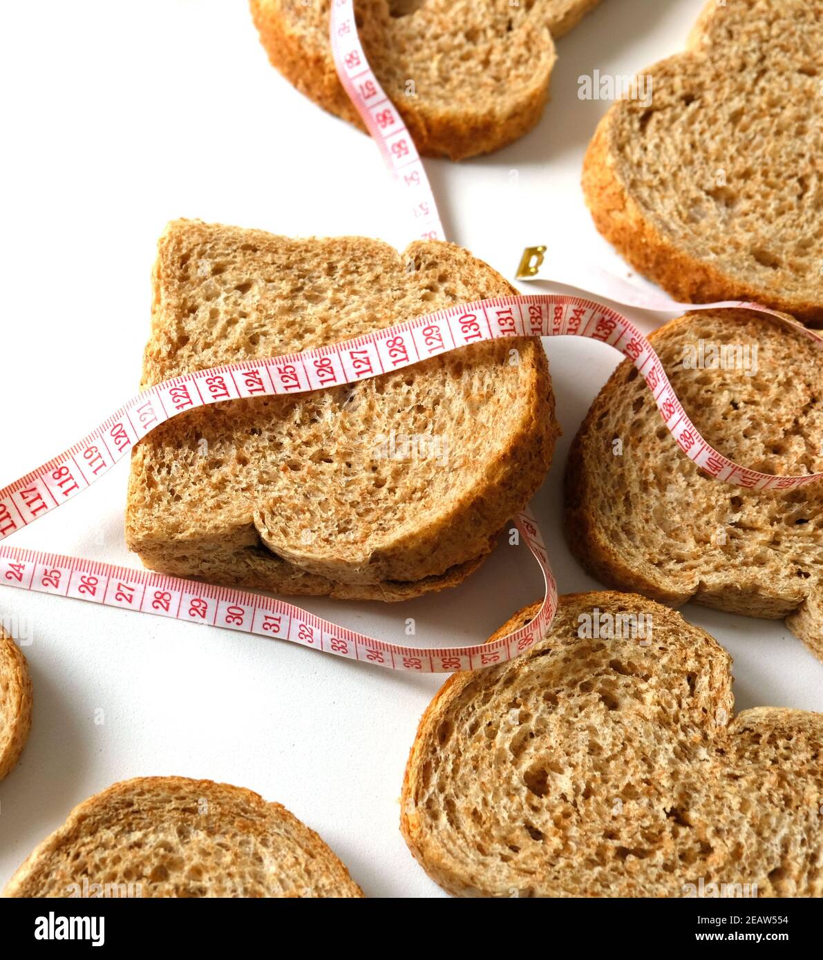 Contra el aumento excesivo de peso en casa, pan de salvado, rebanadas de pan de salvado y una cinta métrica Foto de stock