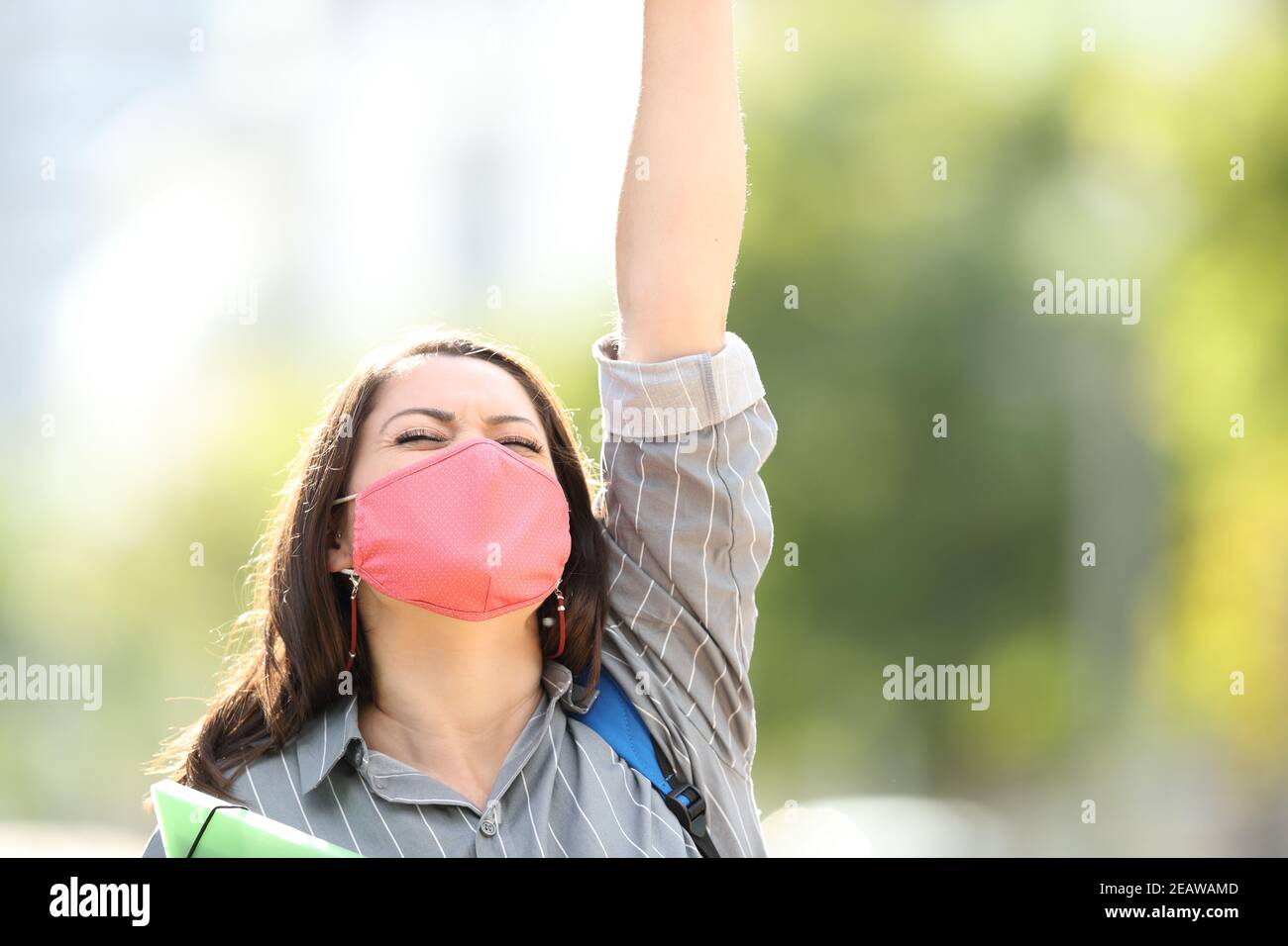 Excitado estudiante con máscara celebrando al aire libre Foto de stock