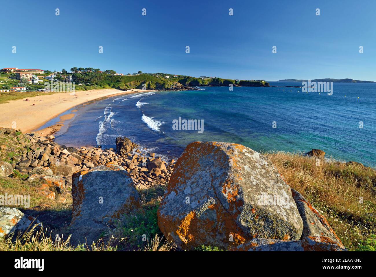 Vista a la playa con una larga playa de arena, rocas y el océano azul Foto de stock
