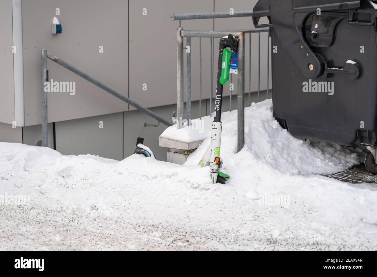 Scooter de cal nevó durante el invierno. Estacionamiento de e-scooters en una acera con mucha nieve. Foto de stock