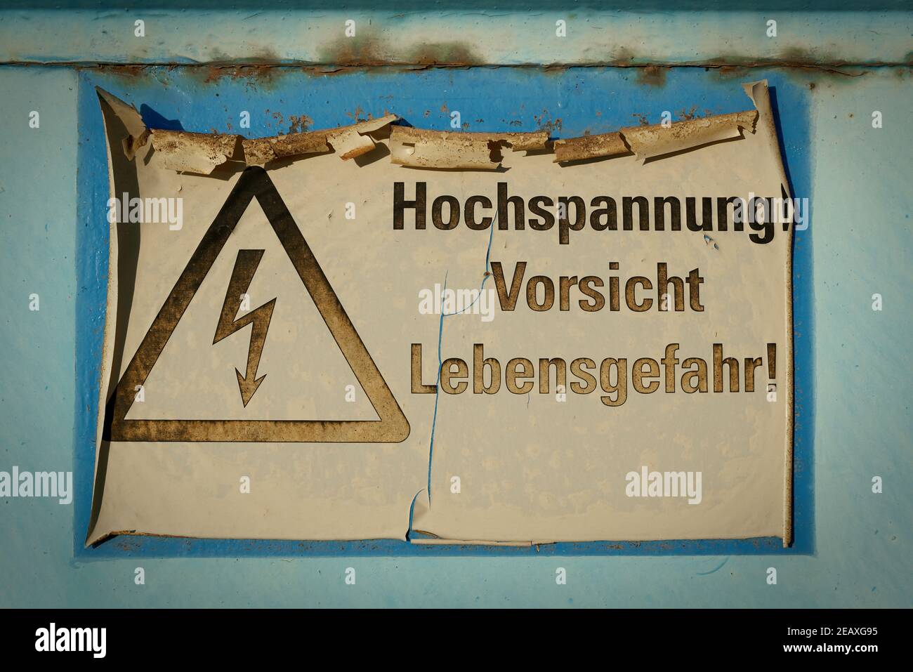 Señal descolorida con la inscripción Alta tensión, peligro de precaución a la vida (Hochspannung Vorsicht Lebensgefahr) Foto de stock