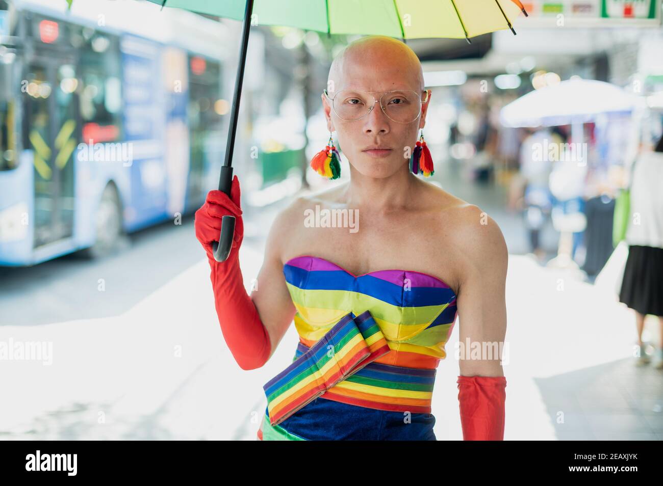 Retrato de una persona de la reina asiática vestida con vestido de colores arcoiris, con guantes rojos y sosteniendo un paraguas de colores arcoiris en Bangkok Tailandia. Foto de stock