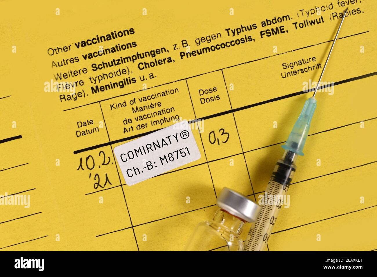 Certificado de vacunación con la vacuna Pfizer-BioNTech COVID-19 Comirnaty con jeringa y vial Foto de stock