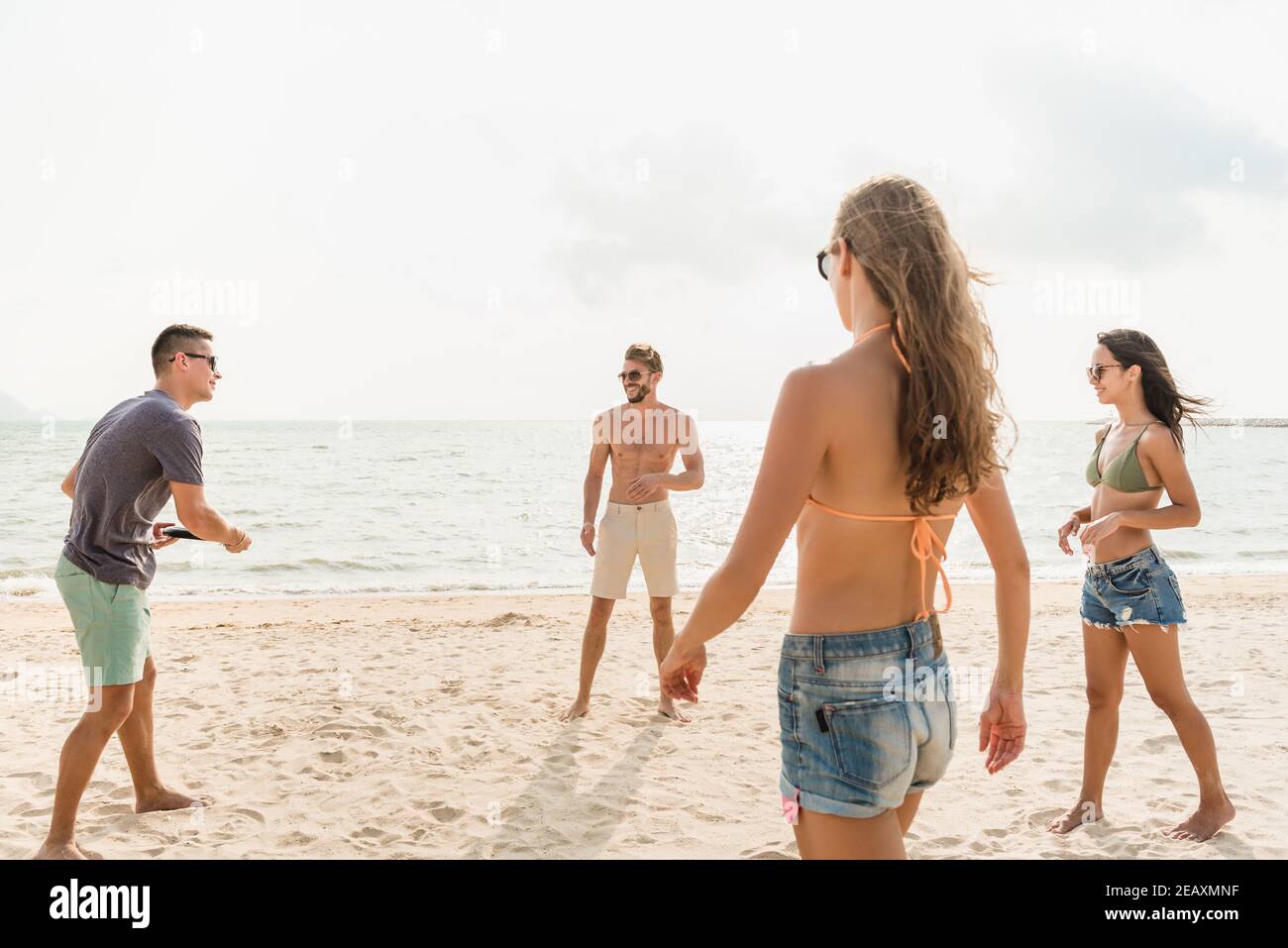 Atractivo grupo de amigos que disfrutan jugando al juego de playa juntos en verano Foto de stock