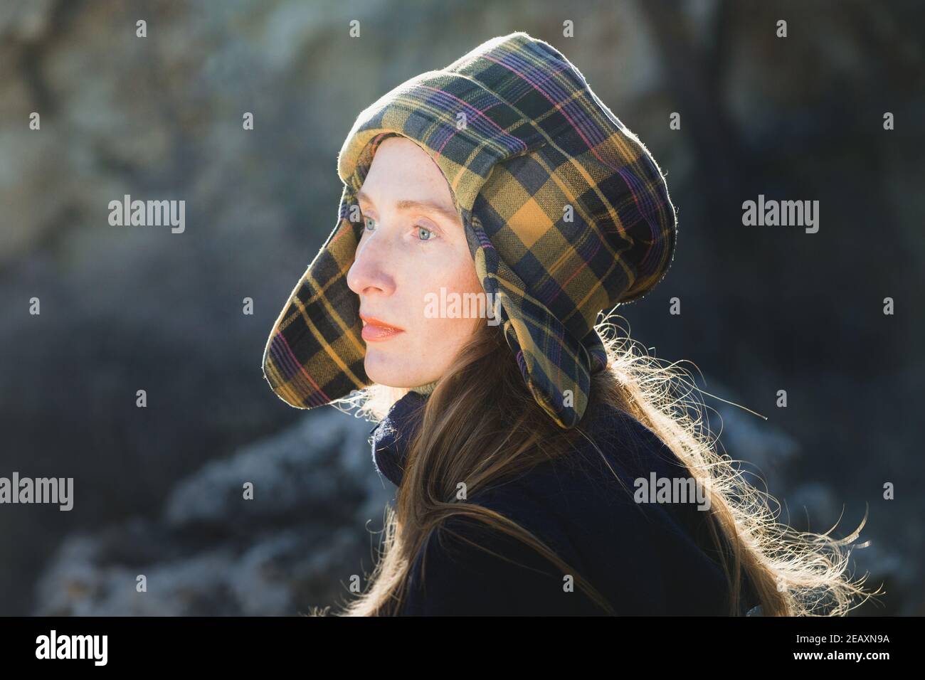 Retrato de una joven en un sombrero en un Pelo de cuadros que revolotea en el viento y brilla en Los rayos del Sol Foto de stock