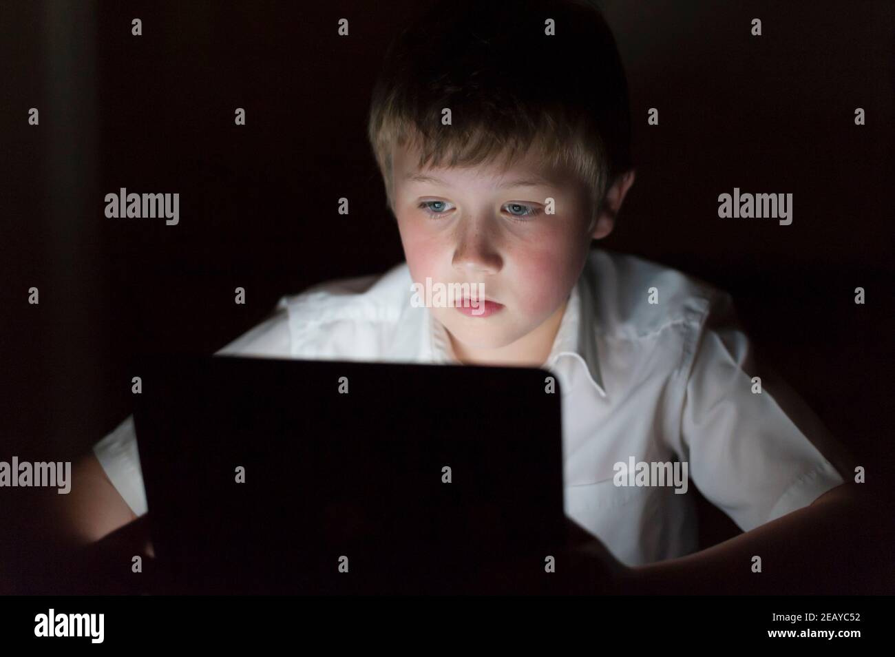 Un niño de 9 años usando una tableta en el por la noche Foto de stock