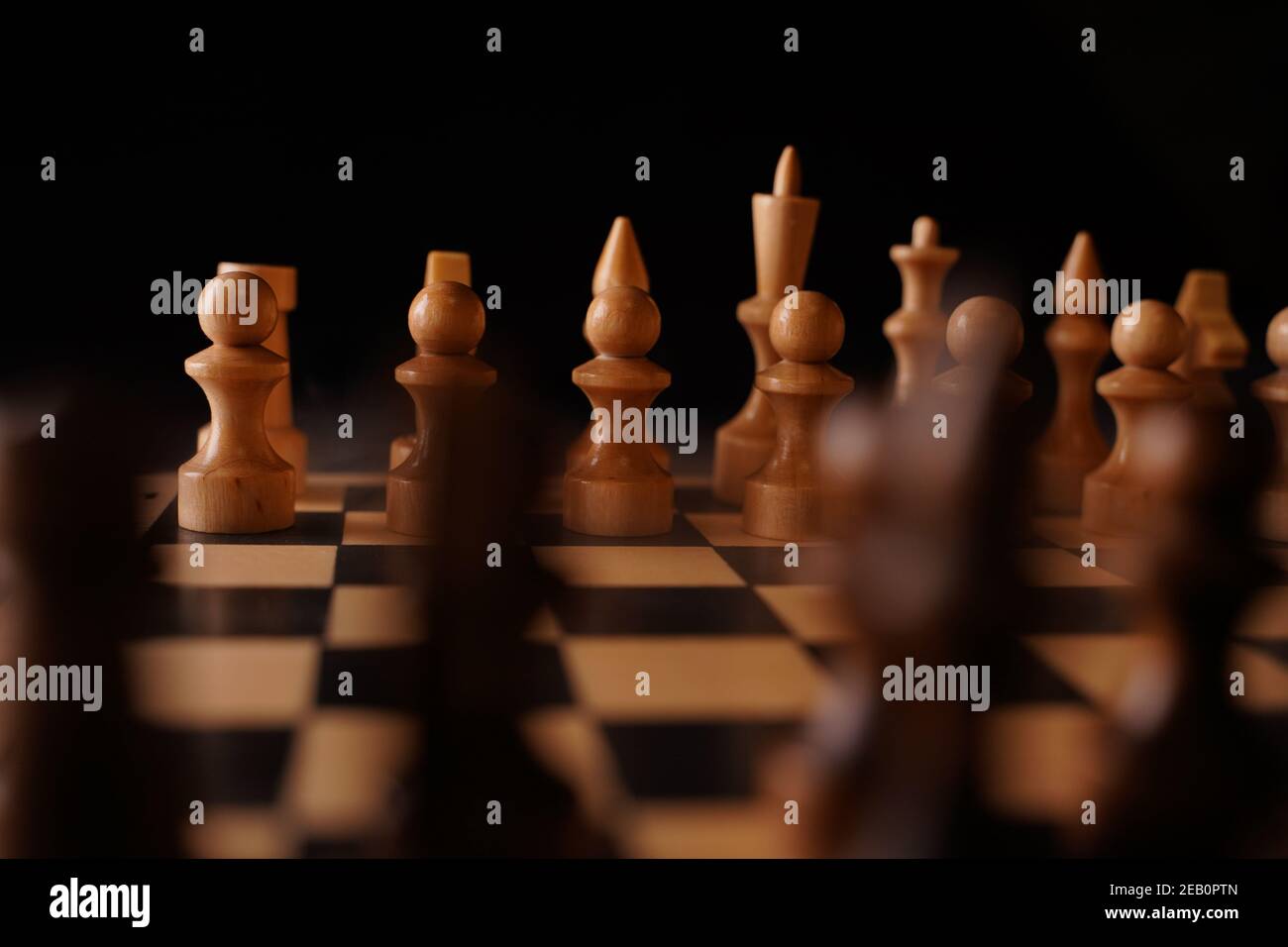 Primer plano de piezas de ajedrez negro a bordo. Dos filas de figuras de  madera sobre tablero de ajedrez sobre fondo negro. Concepto de inteligente,  lógico y estratégico g Fotografía de stock -