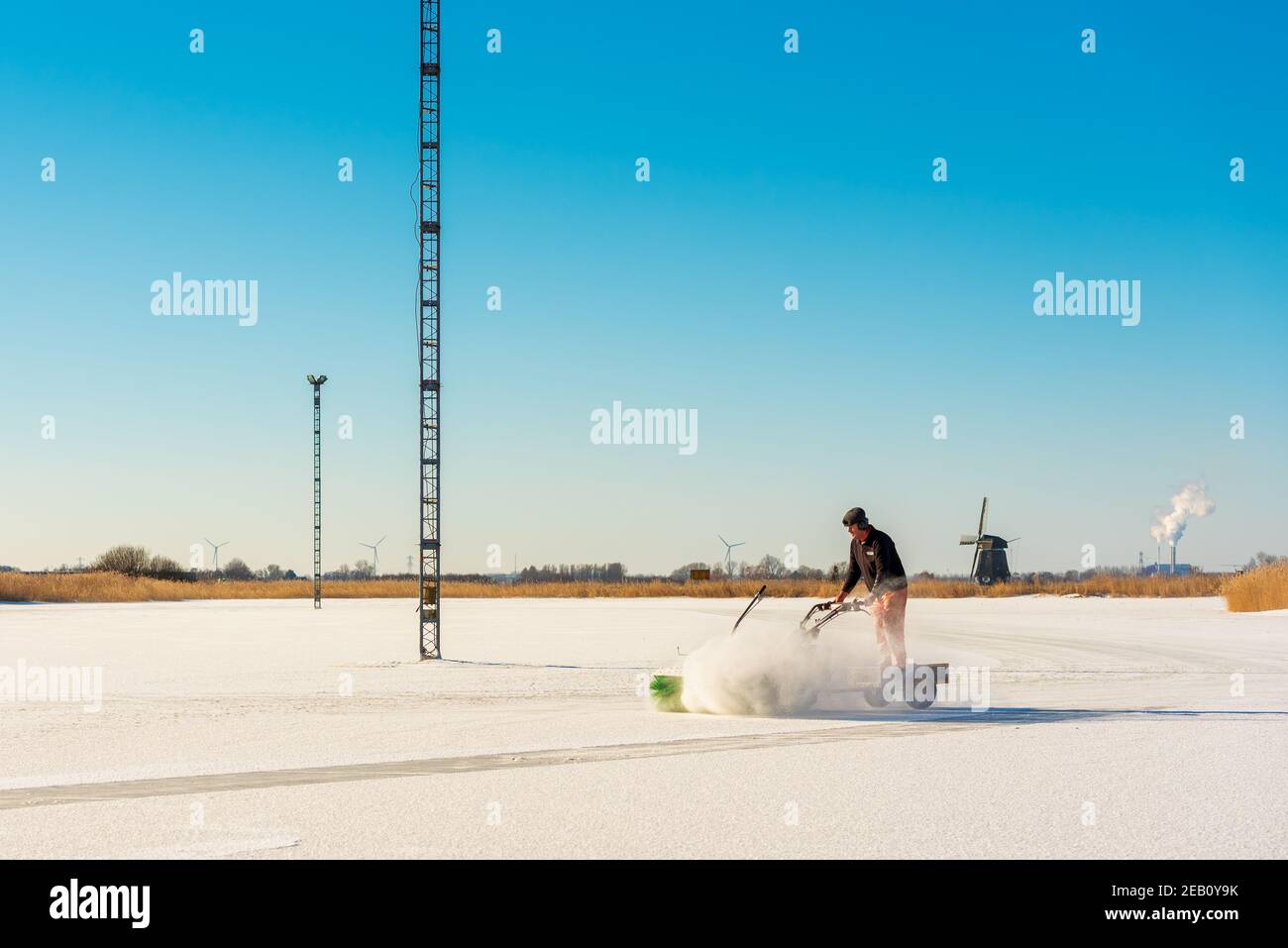 Miembro del club de patinaje sobre hielo se descasse de la nieve natural Pista de patinaje sobre hielo en un campo de fútbol sumergido en Grootschermer Países Bajos en febrero de 2021 Foto de stock