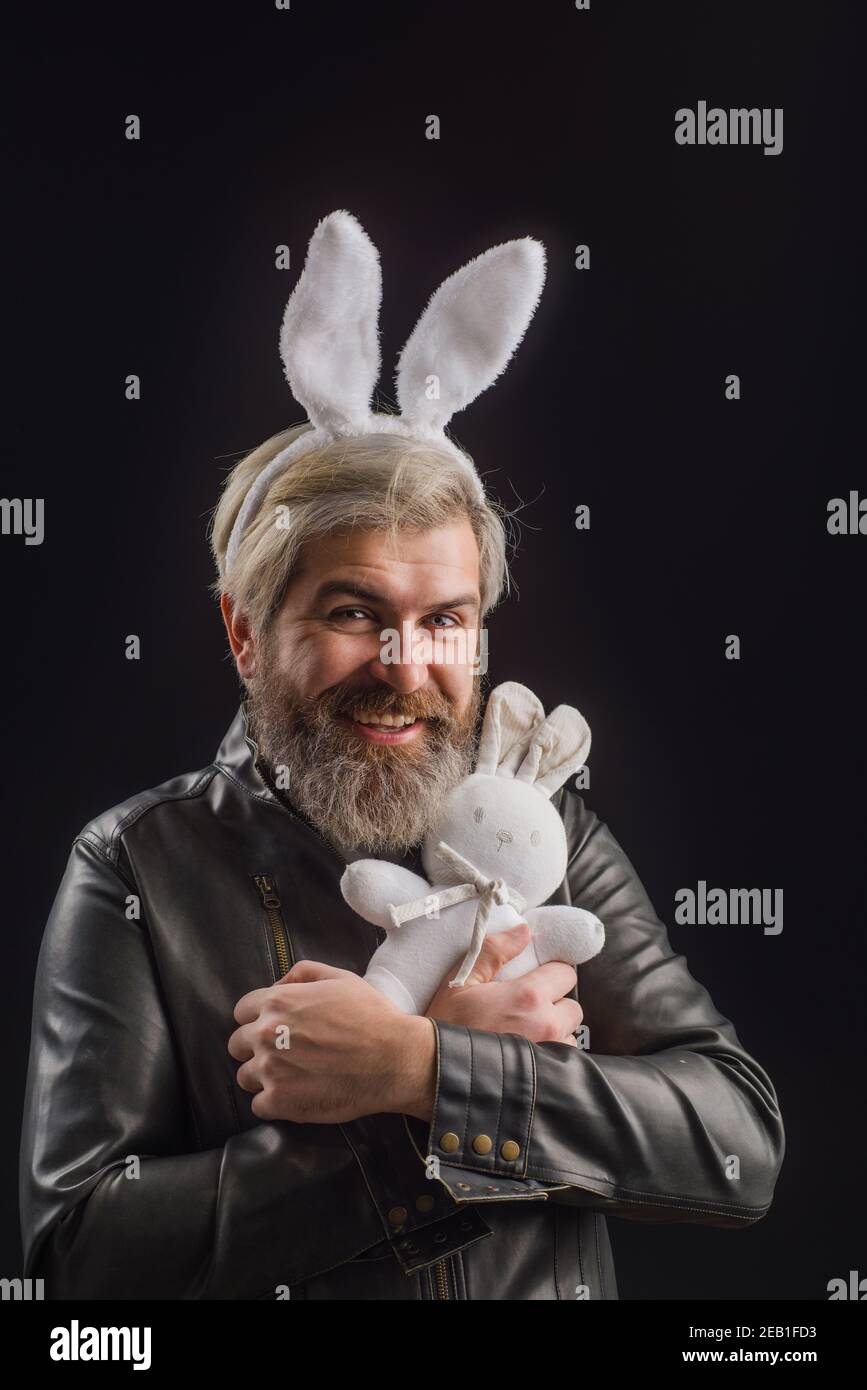 Feliz día de Pascua. Hombre sonriente en orejas de conejo con peluche de conejito. Foto de stock