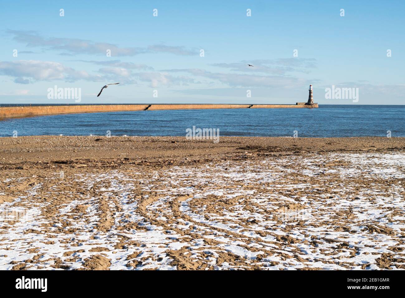 Una playa y un muelle vacíos de Roker con una capa ligera de nieve en febrero de 2021, Sunderland, noreste de Inglaterra, Reino Unido Foto de stock