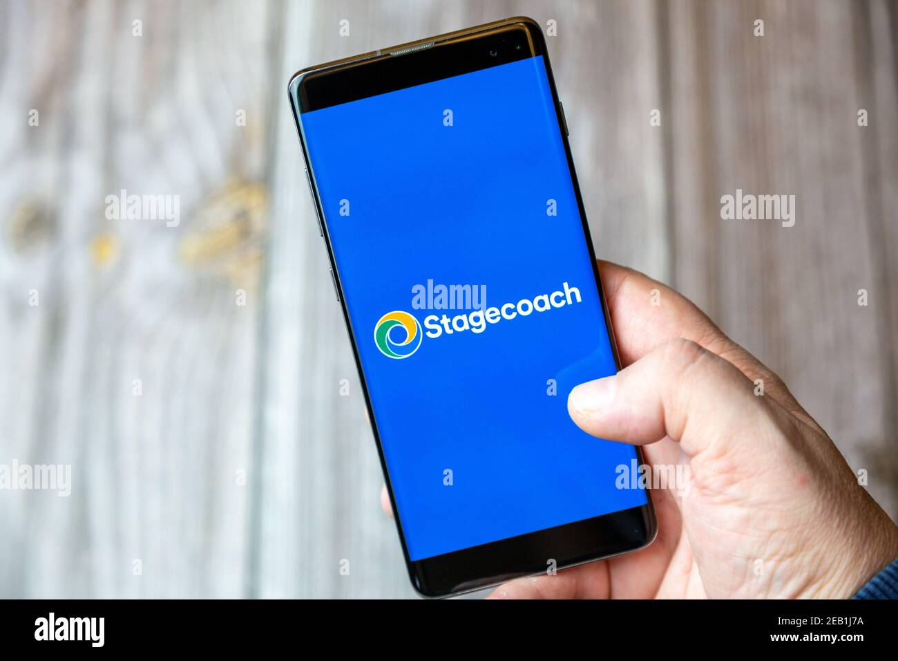 Un teléfono móvil o celular que está en manos de un Mano con la aplicación Stagecoach abierta en la pantalla Foto de stock