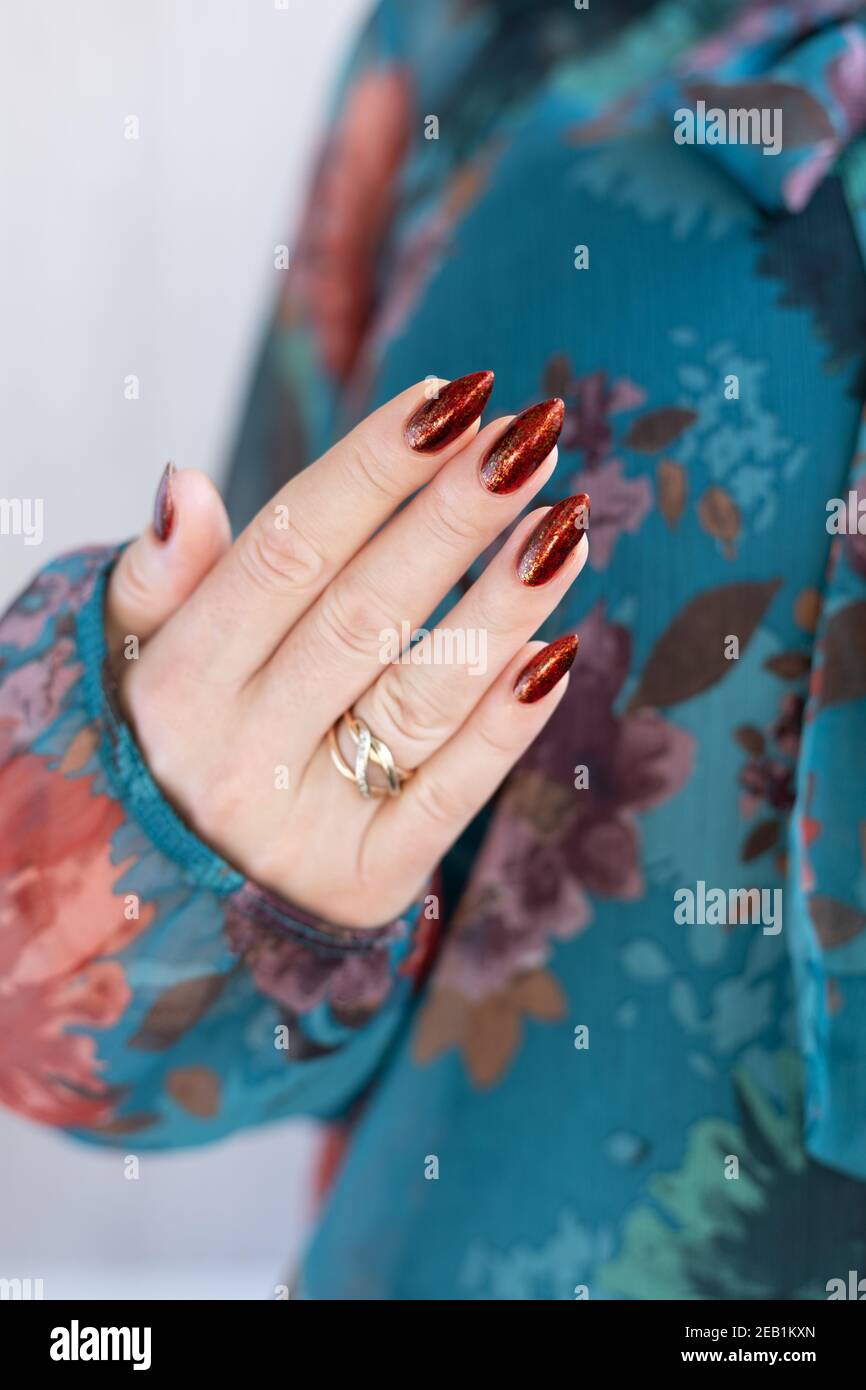 Mano femenina con uñas largas y marrón dorado, manicura sostiene una  botella de esmalte de uñas Fotografía de stock - Alamy