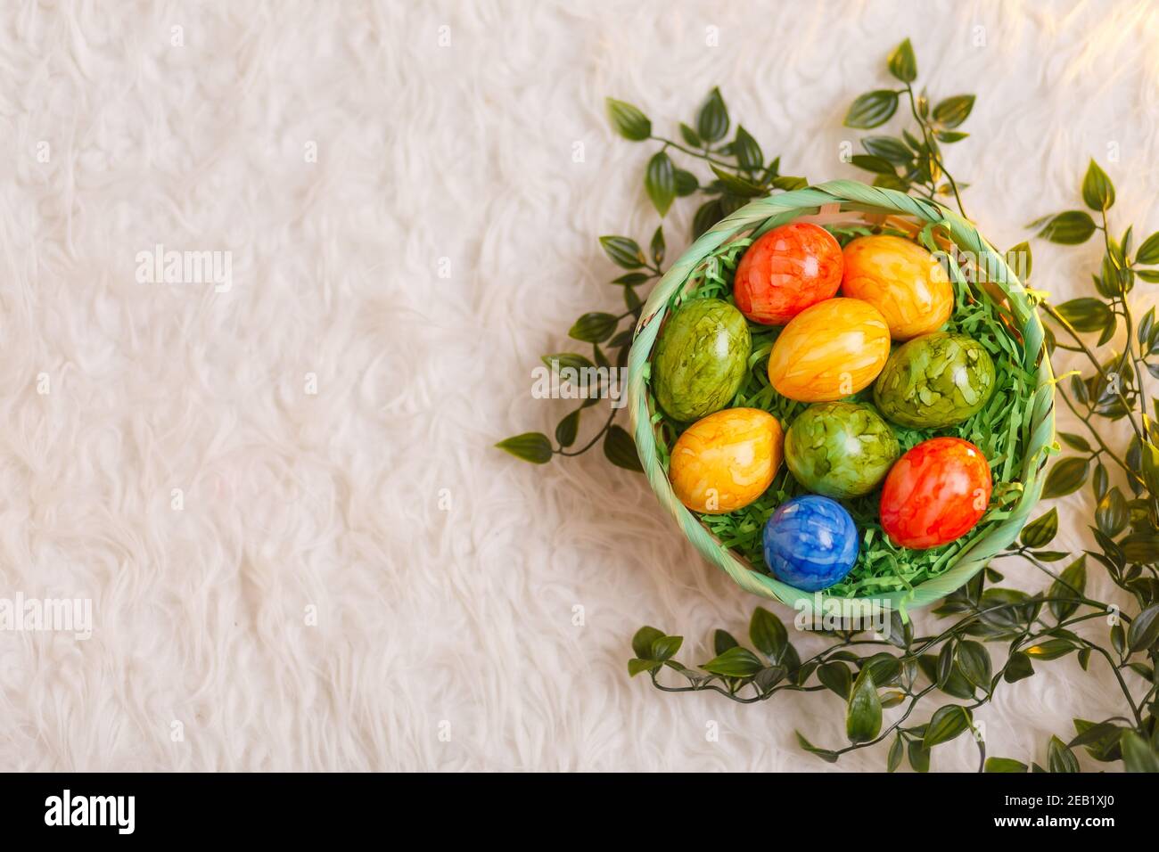 Tarjeta de Pascua. Composición plana con huevos de pascua en una cesta sobre fondo blanco. Foto de stock