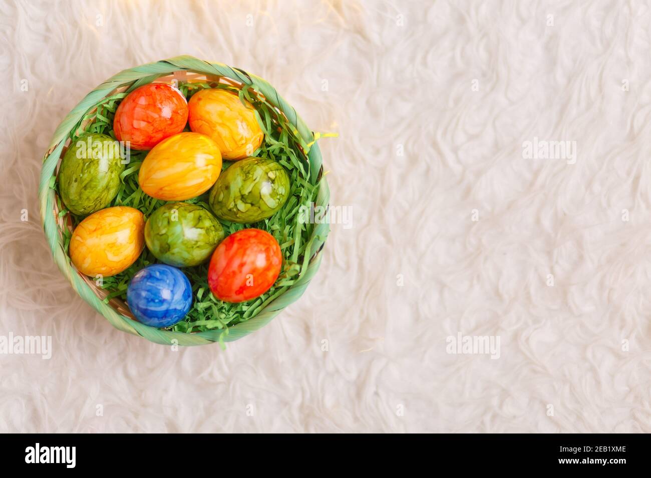 Tarjeta de Pascua. Composición plana con huevos de pascua en una cesta sobre fondo blanco. Foto de stock