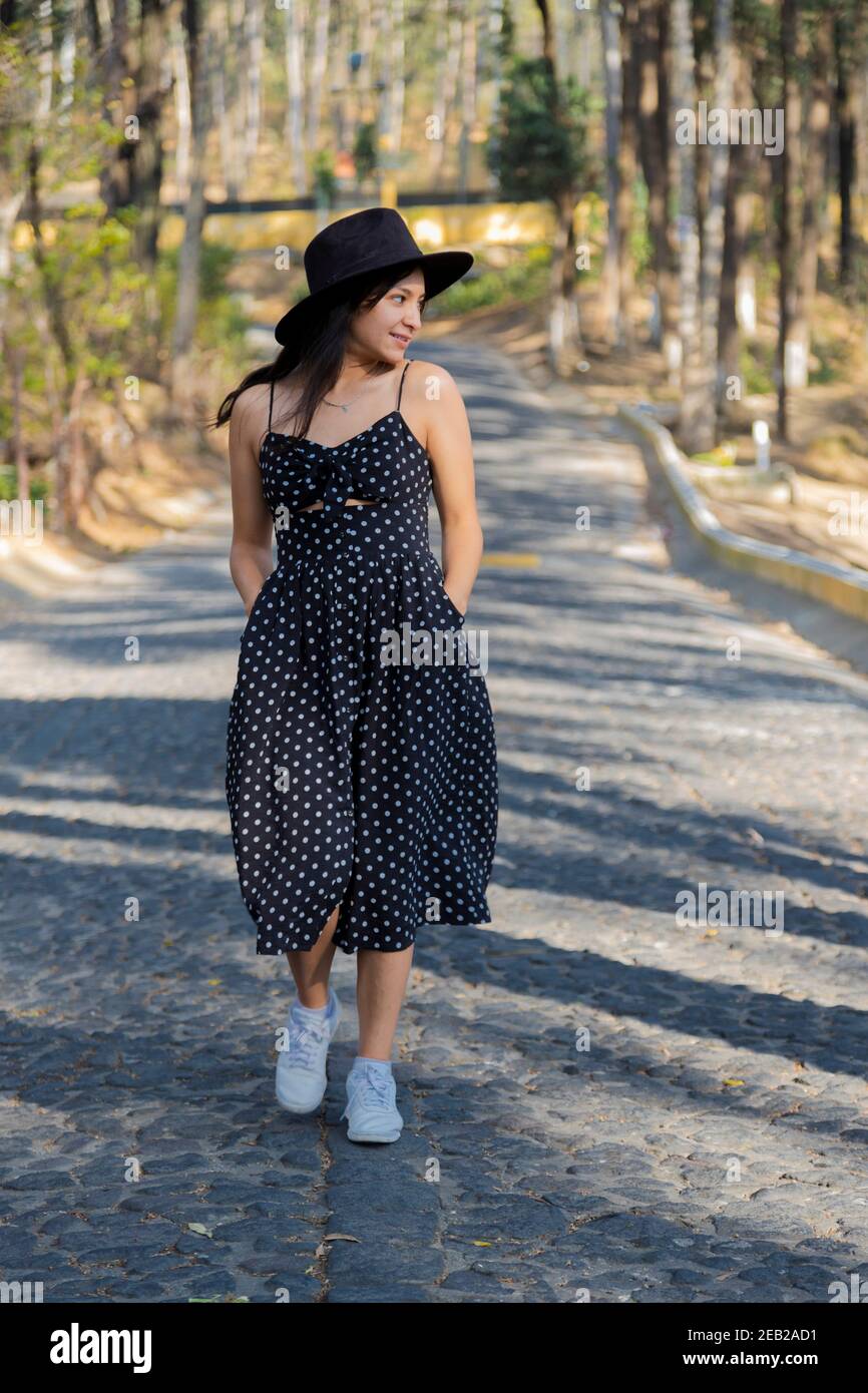 Mujer hispana con vestido negro caminando en el medio de la calle en el  parque natural - para mujer joven un paseo en medio de la naturaleza en un  camino de Fotografía