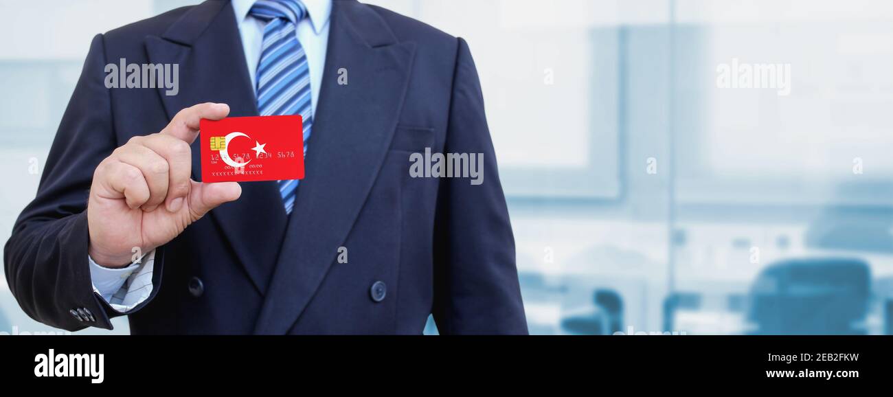 Imagen recortada de un hombre de negocios con tarjeta de crédito de plástico con bandera impresa de Turquía. Fondo borroso. Foto de stock